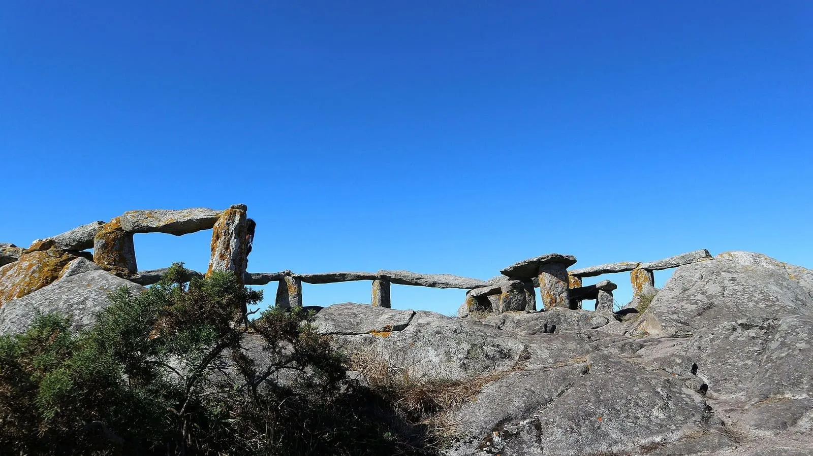 Una barandilla de madera y losas de piedra junto al borde del Buraco do Inferno, en la costa de Ons