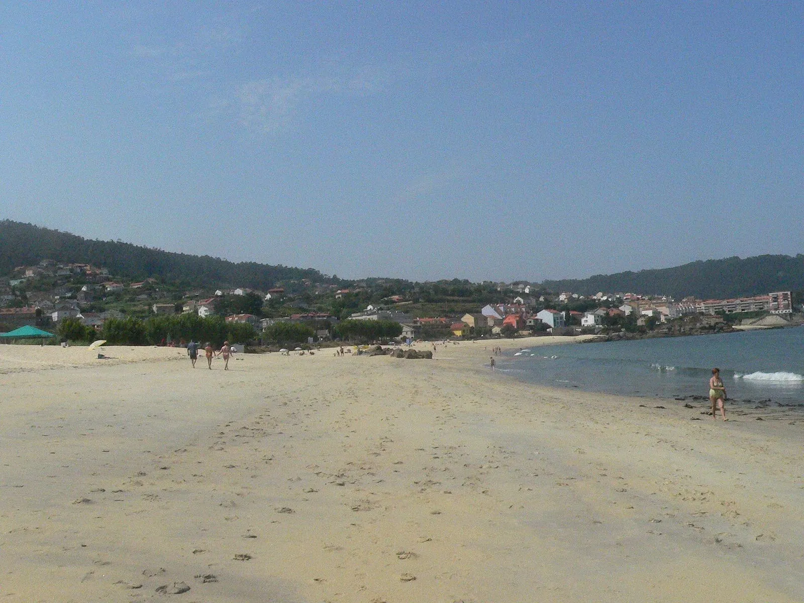 Playa de Agrelo, de arena dorada, con las casas de Bueu y los montes al fondo