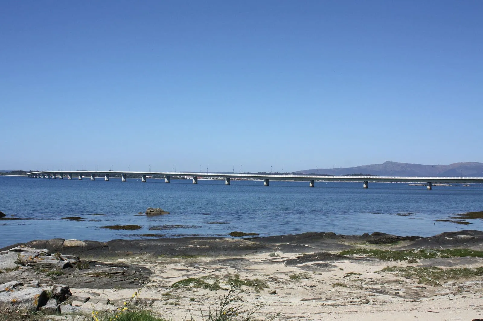 El puente de A Illa de Arousa cruzando la ría, visto desde unas rocas