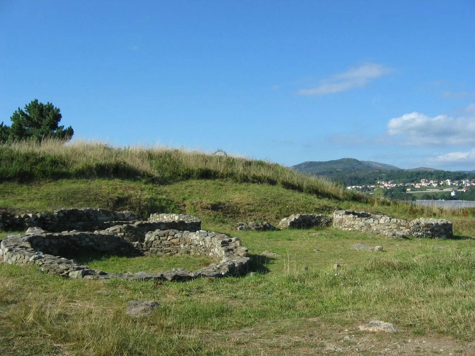 Base circular de piedra de una vivienda del castro de Neixón, con la costa al fondo