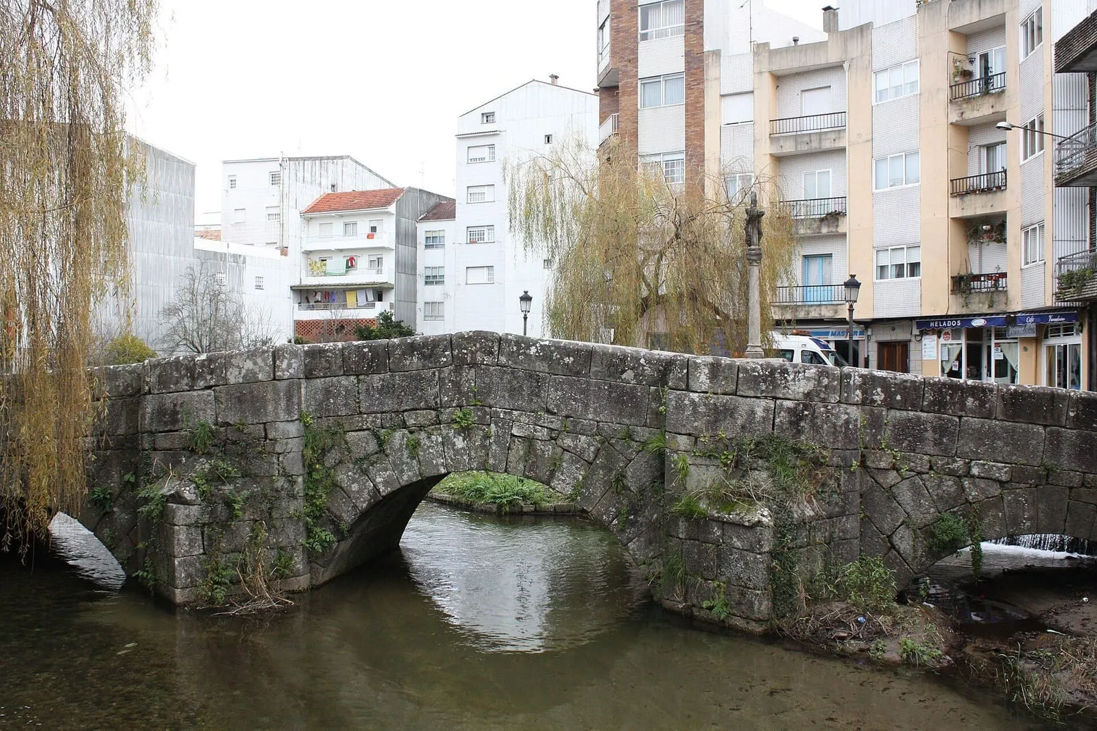 La ponte da Bermaña, con sus arcos de piedra sobre el río y los edificios del centro de Caldas detrás