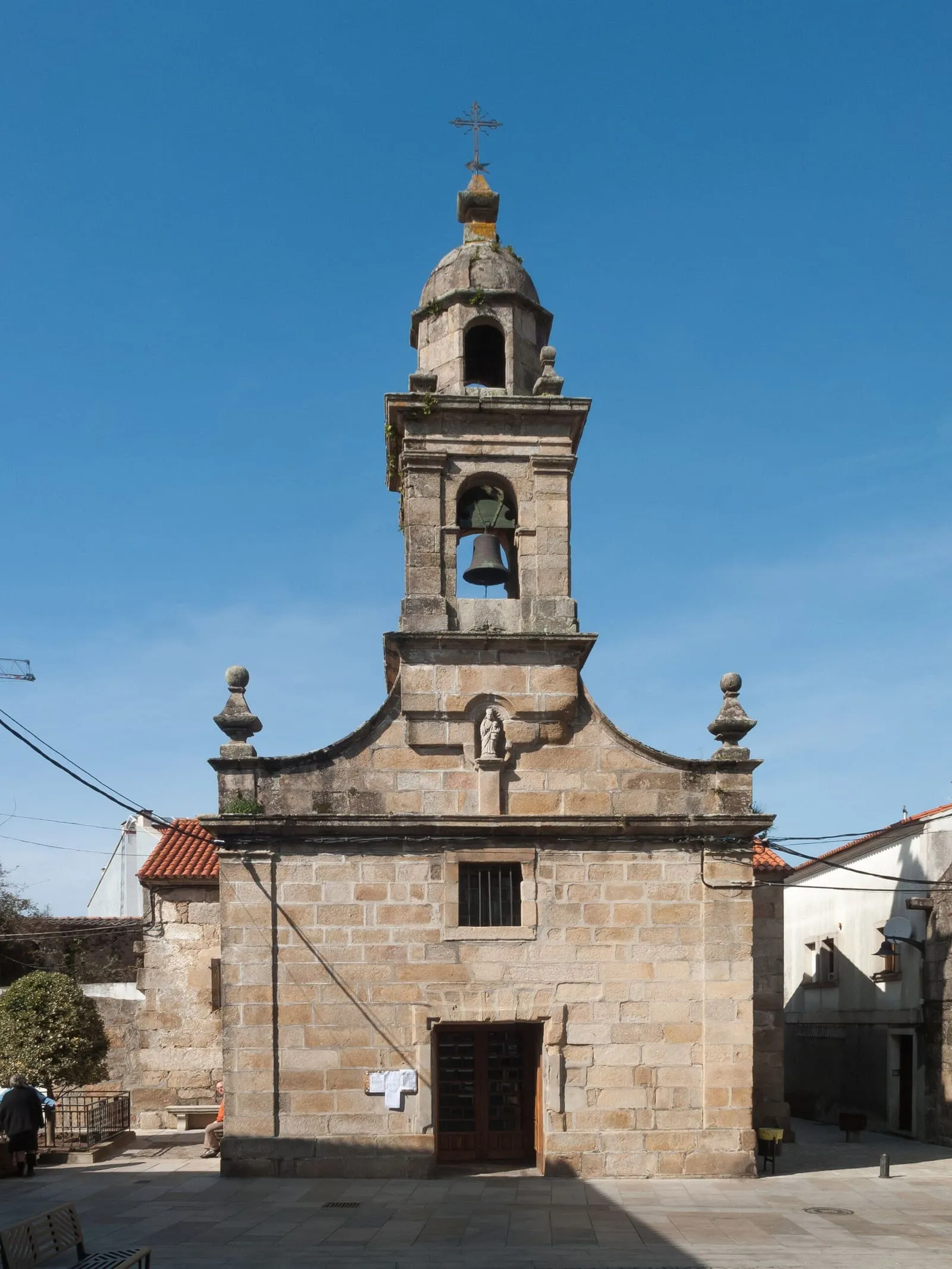 La capilla del Hospital de Cambados, con su fachada de piedra y su espadaña, entre casas del casco