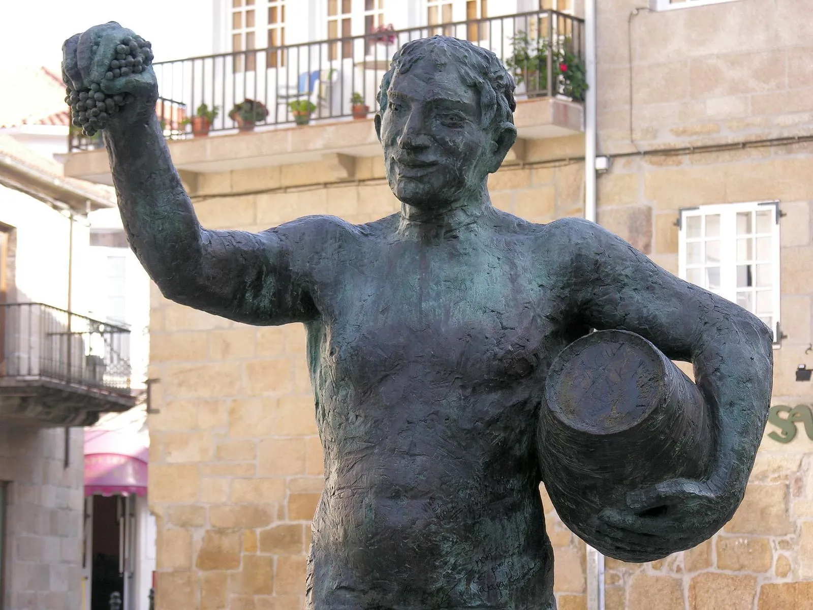 La escultura de Baco, un hombre que levanta un racimo de uvas y sostiene un cesto, en una plaza de Cambados
