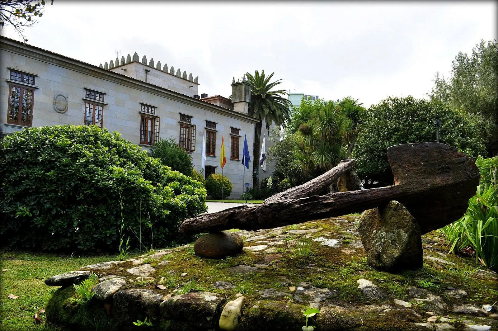 El Pazo de Bazán, hoy parador, con su fachada de piedra clara y un jardín con un ancla antigua