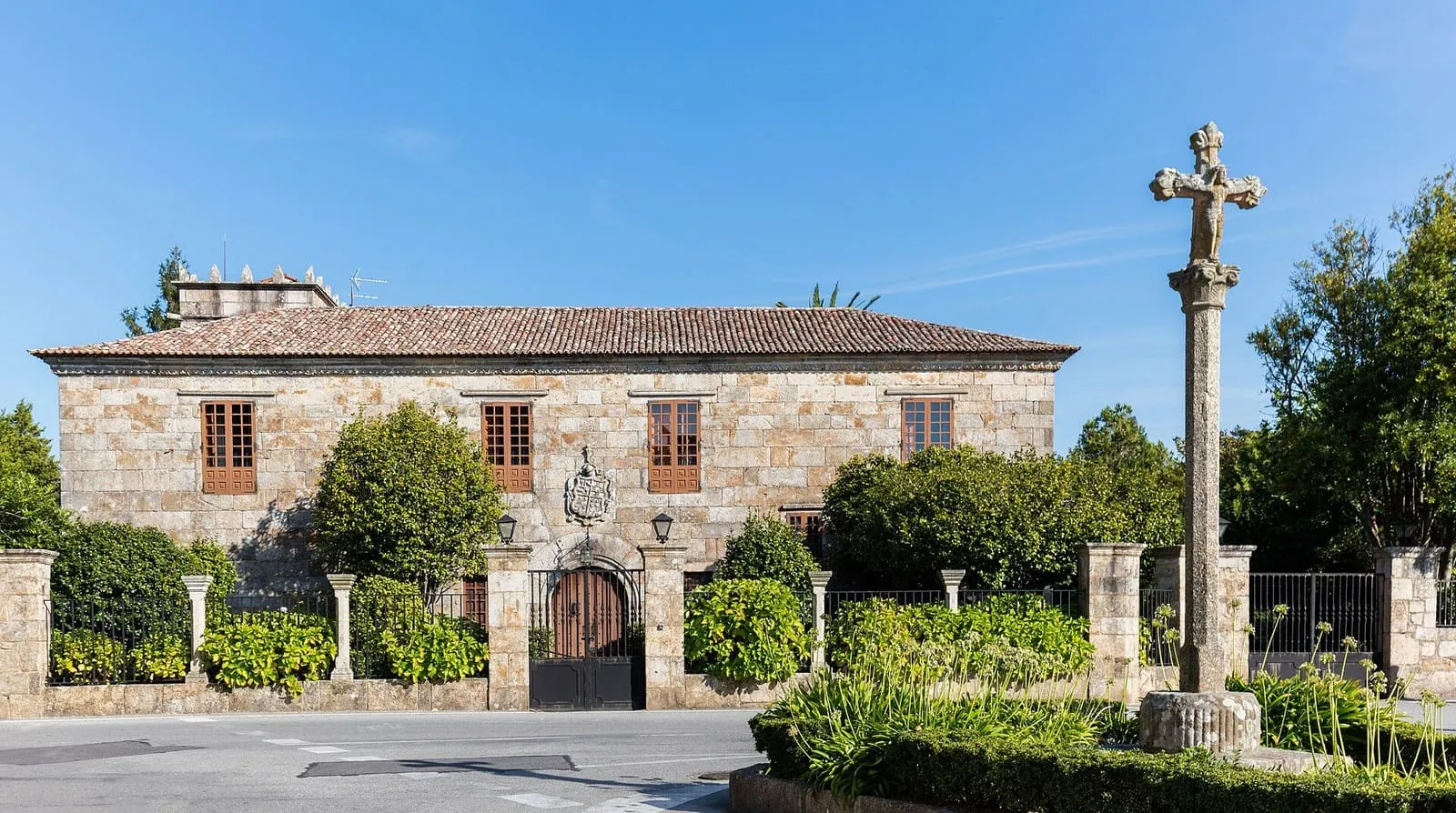 El pazo de Ulloa de Cambados, una casa de piedra con cruceiro delante, bajo un cielo azul