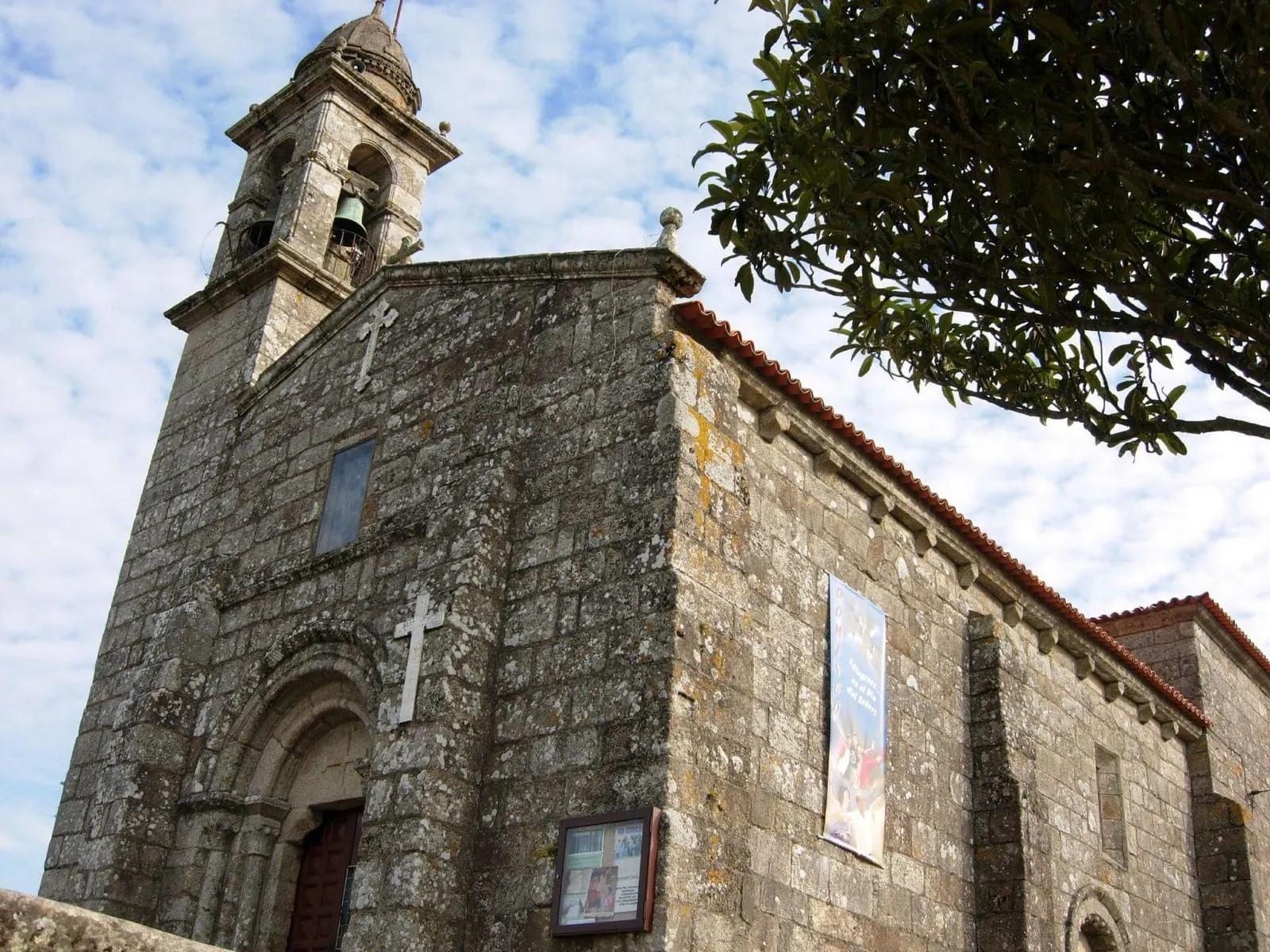 La iglesia de San Salvador de Meis, de piedra, con su torre campanario y la portada lateral
