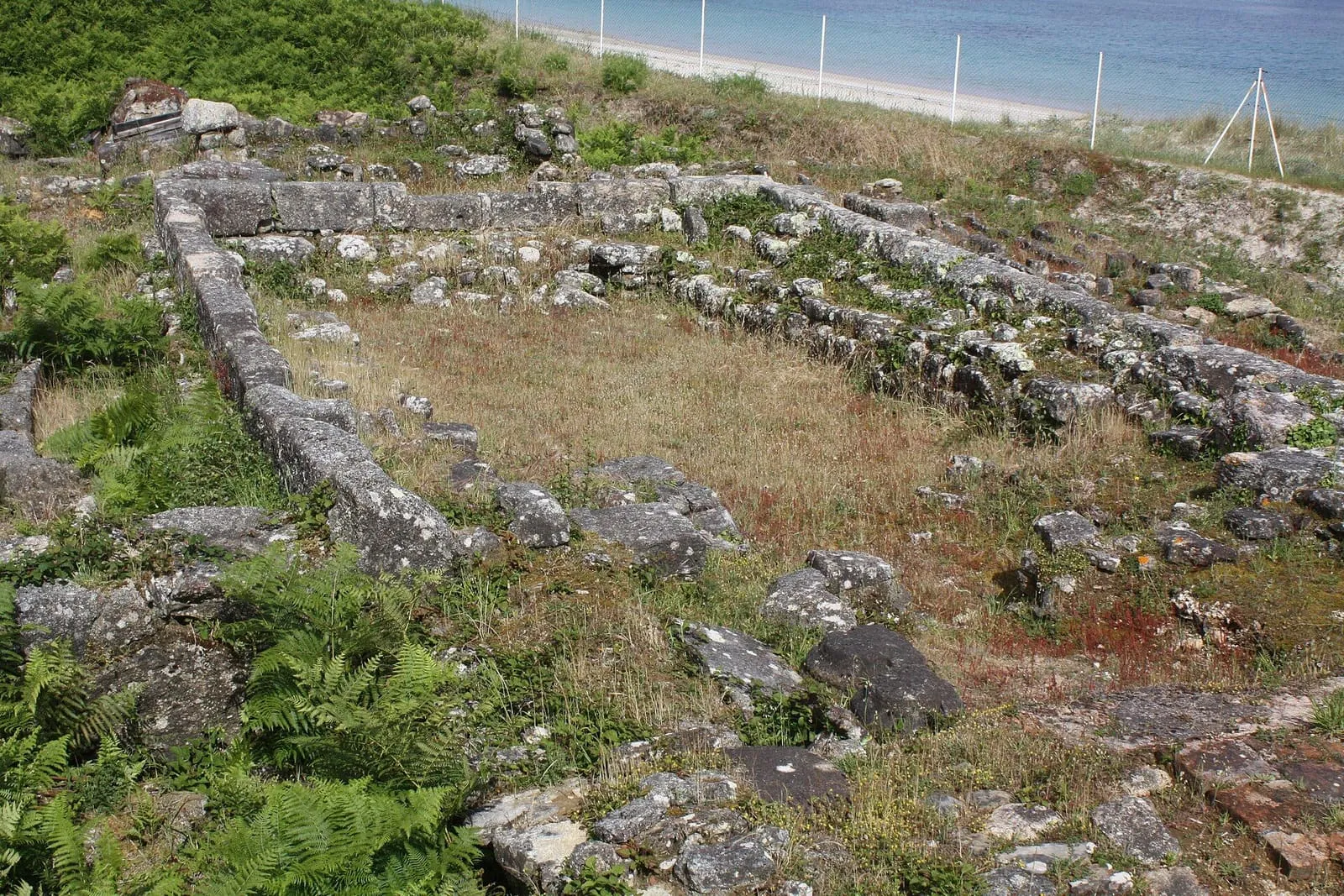 Los muros de piedra del yacimiento de Adro Vello sobre una plataforma de hierba junto al mar