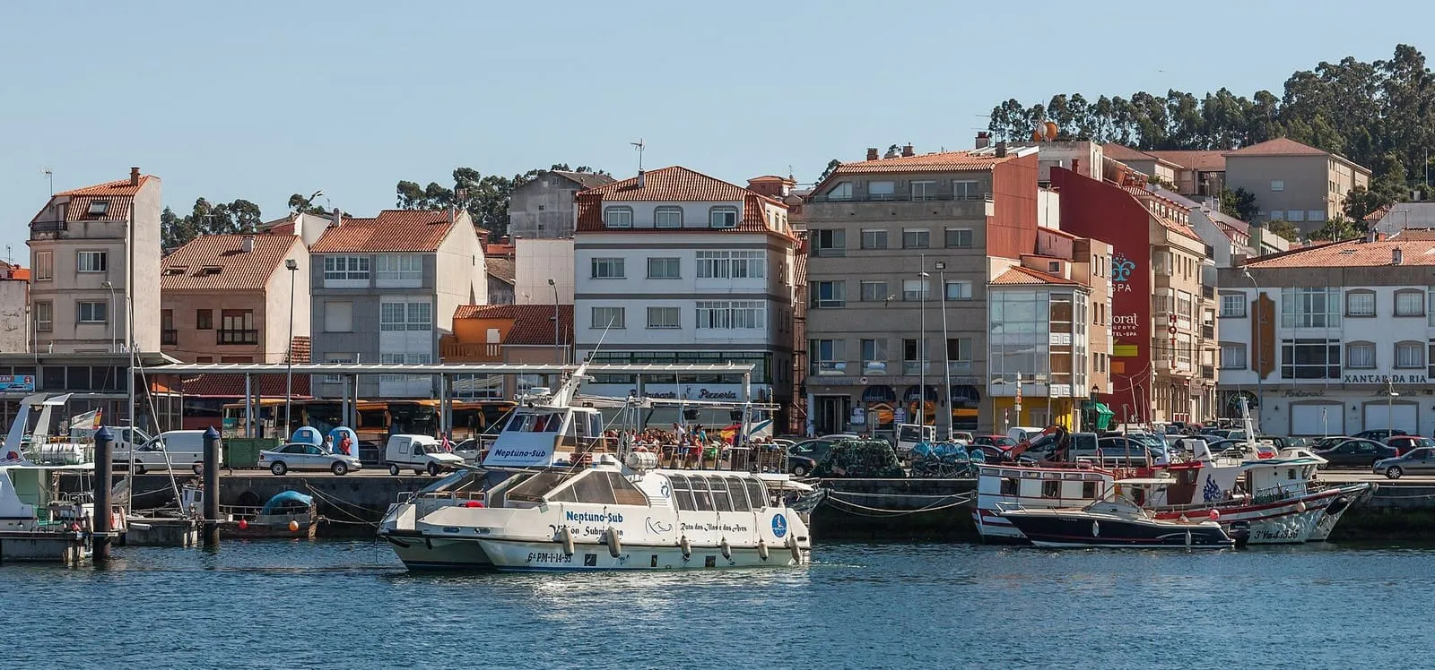 Puerto de O Grove con las casas frente al muelle y un barco de excursiones