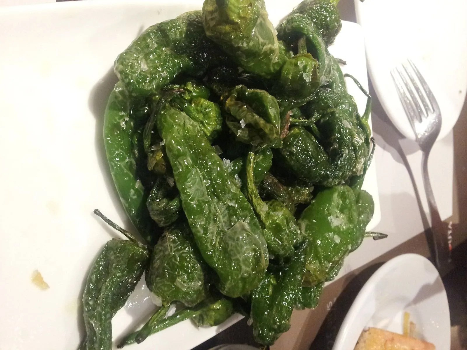 Un plato de pimientos de Padrón fritos con sal gorda, con un tenedor