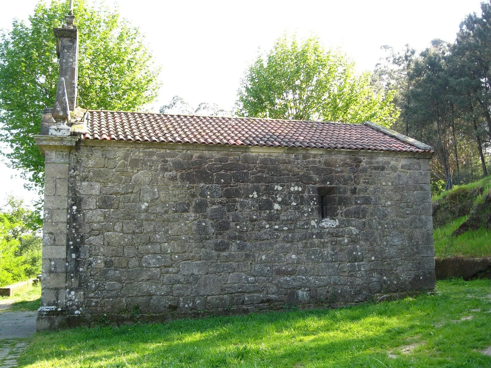 La pequeña capilla de piedra de Santiaguiño do Monte entre árboles, en el monte de San Gregorio