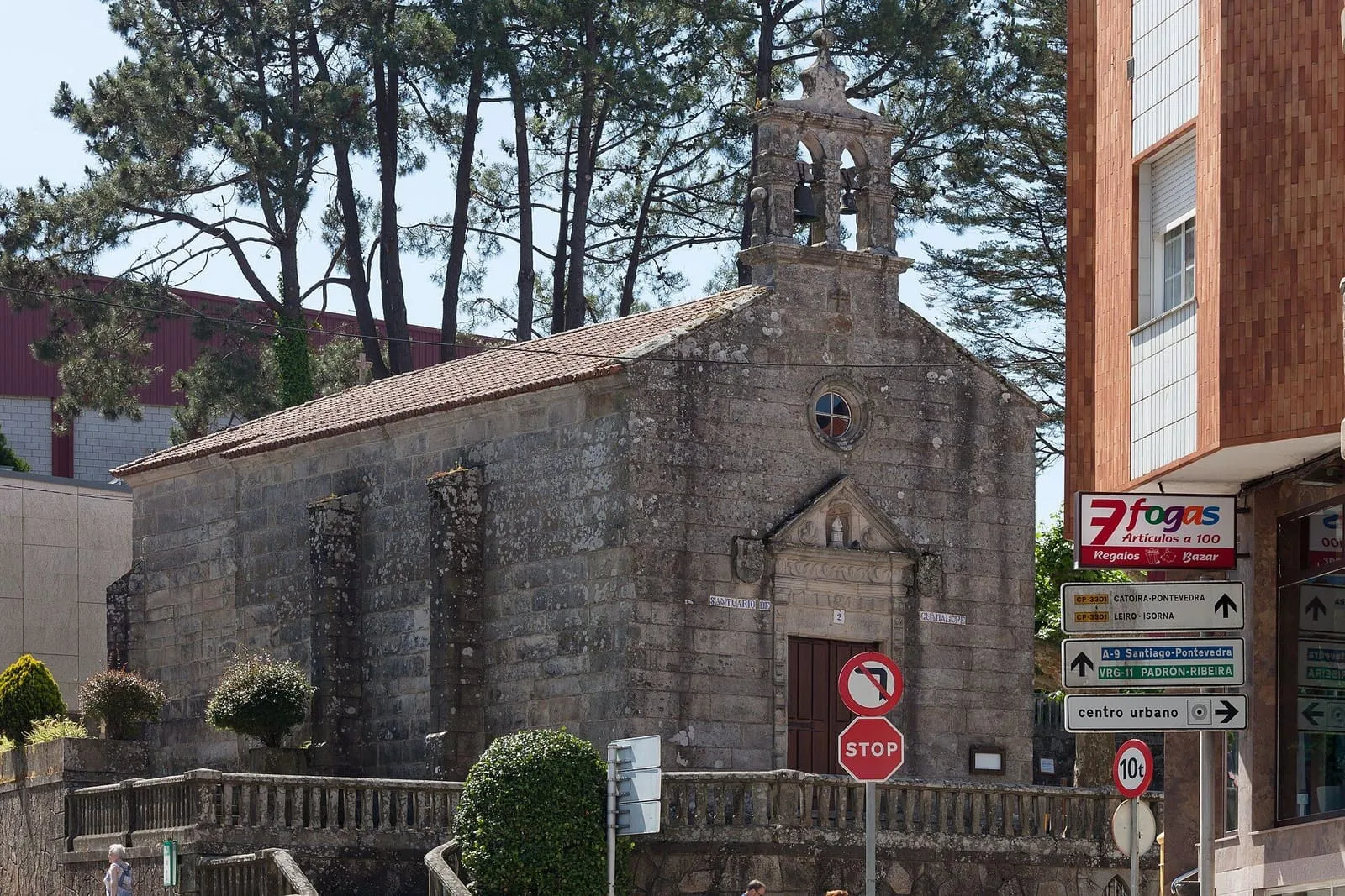 El santuario de Guadalupe de Rianxo, una capilla de piedra con su balaustrada, junto a una calle del pueblo