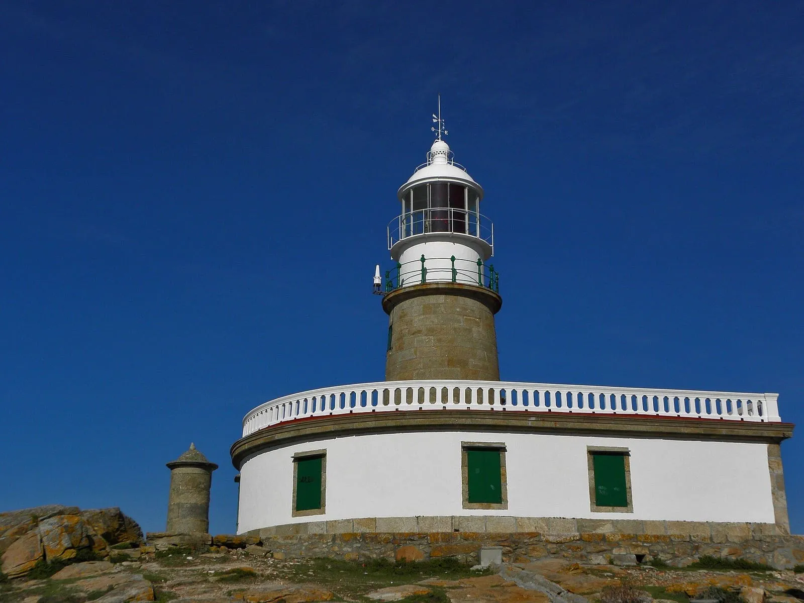 Faro de Corrubedo y su edificio blanco bajo un cielo azul intenso