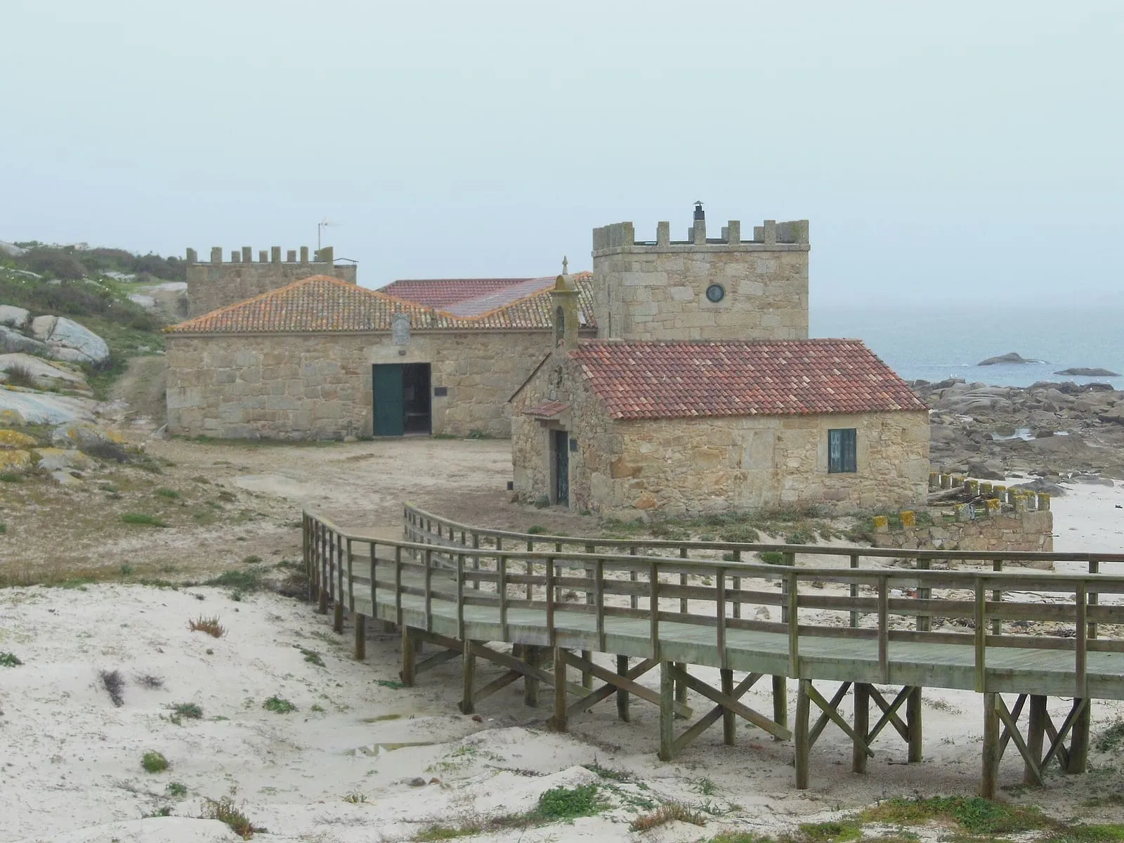La capilla de Santa Catarina y el antiguo almacén de salazón con torres almenadas, junto a la pasarela de madera, en la isla de Sálvora