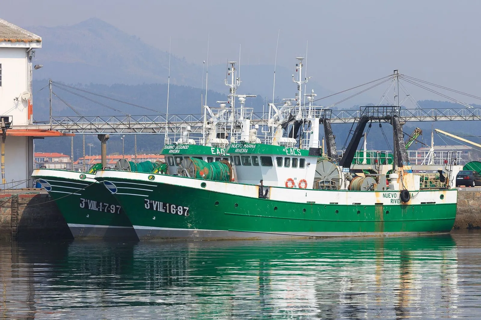 Dos barcos pesqueros verdes amarrados en el puerto de Ribeira