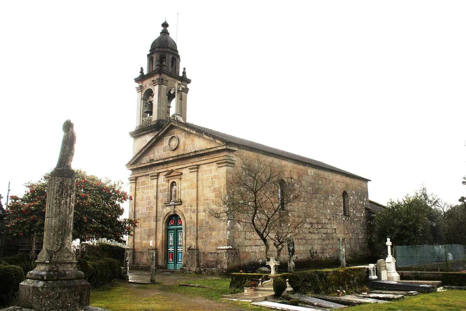Iglesia de piedra con torre y cruz de piedra en el cementerio, en Setecoros