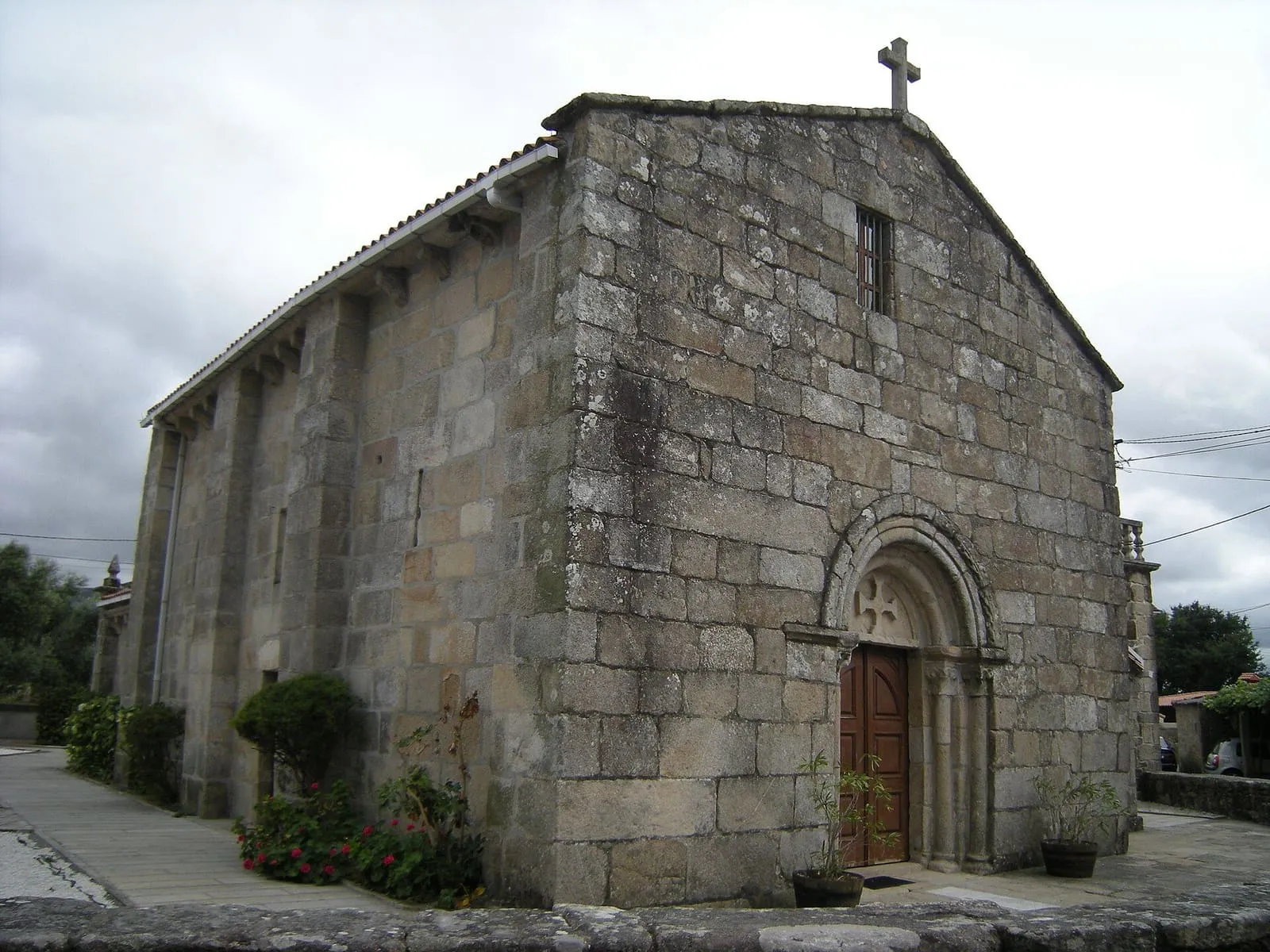 La iglesia románica de Santa Cristina de Campaña, de granito, con su portada y el ábside