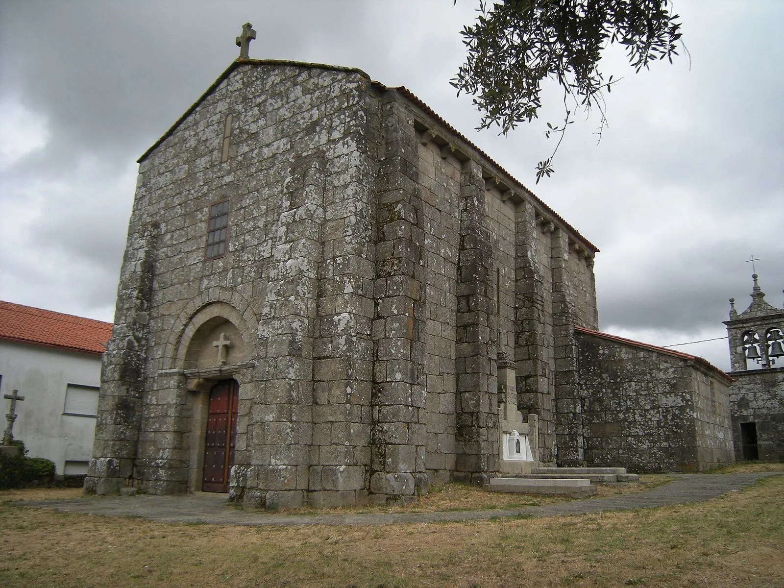 La iglesia de Santa María de Xanza, de granito, con ábside rectangular y un portal de arco de medio punto