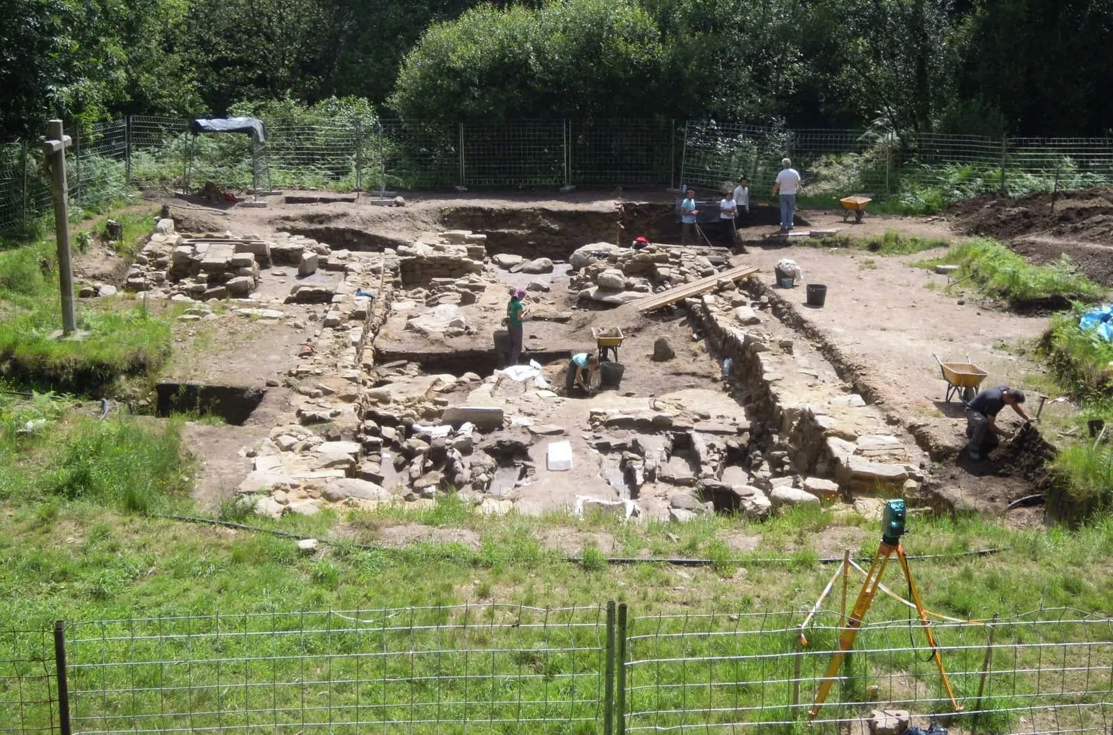 Excavación de la iglesia vieja de Santa Comba de Louro: muros de piedra y cimientos sobre un prado