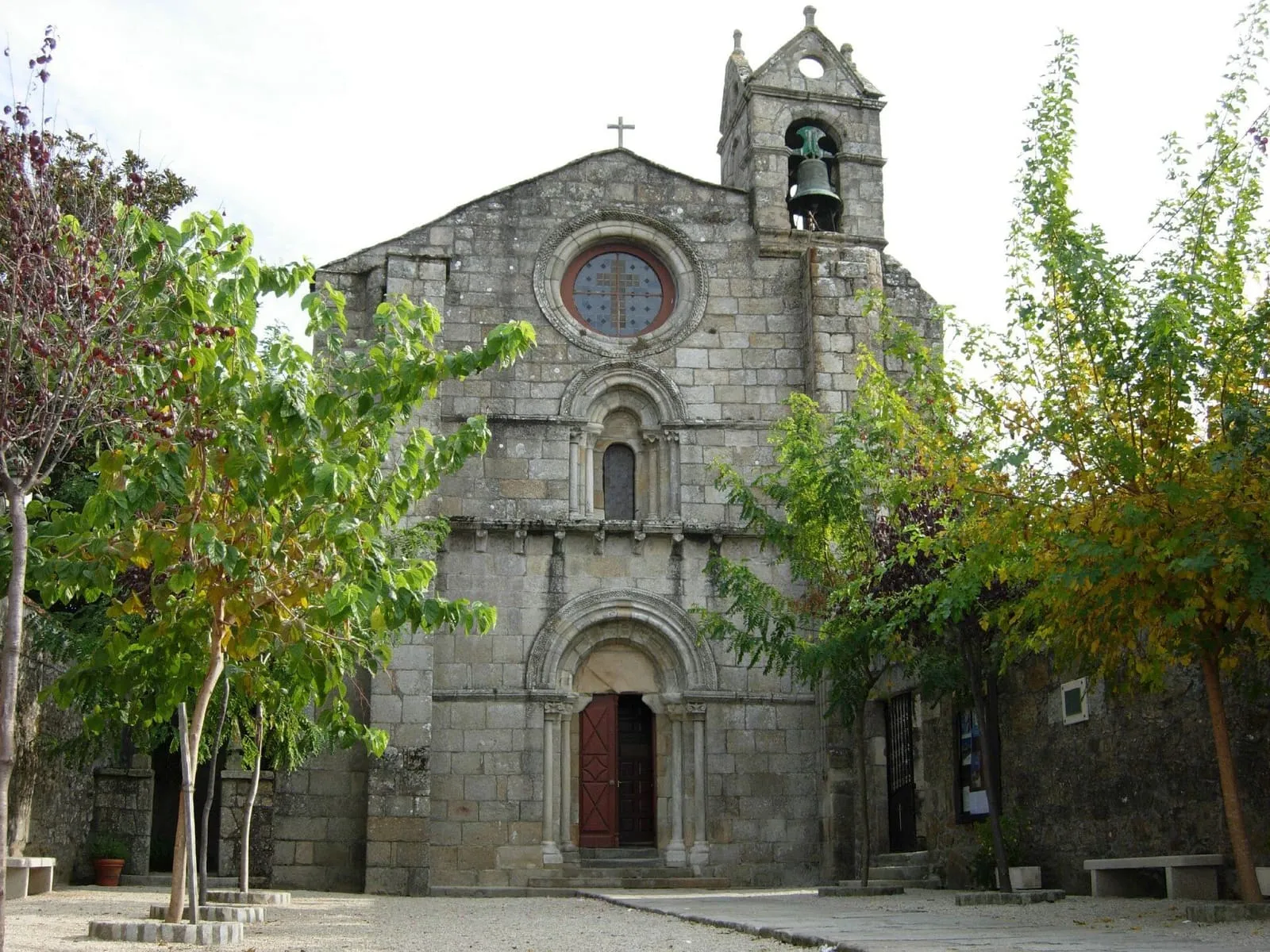 Fachada románica de la iglesia de San Martiño de Sobrán, con rosetón, ventana y portada, entre árboles
