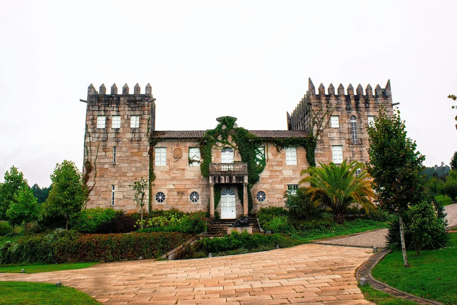 El pazo Baión, con dos torres almenadas y un jardín con palmeras, rodeado de viñedos de albariño