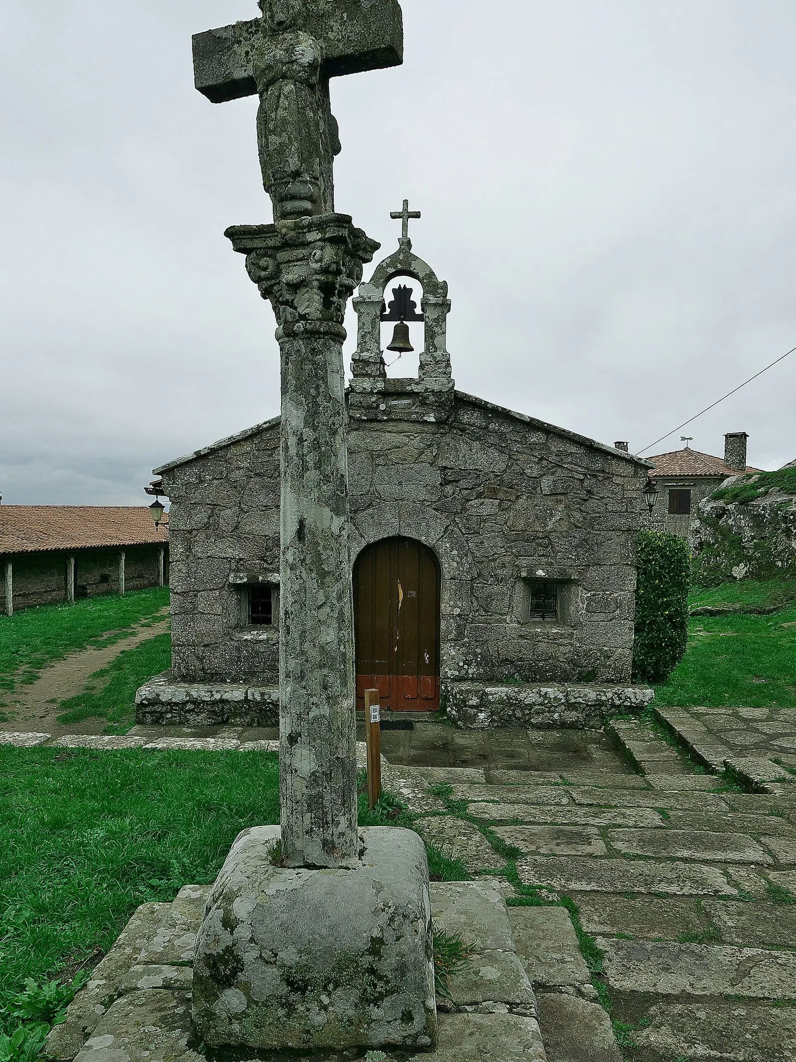 La pequeña capela de Santa Trega, de piedra con una espadaña, con un cruceiro en primer plano