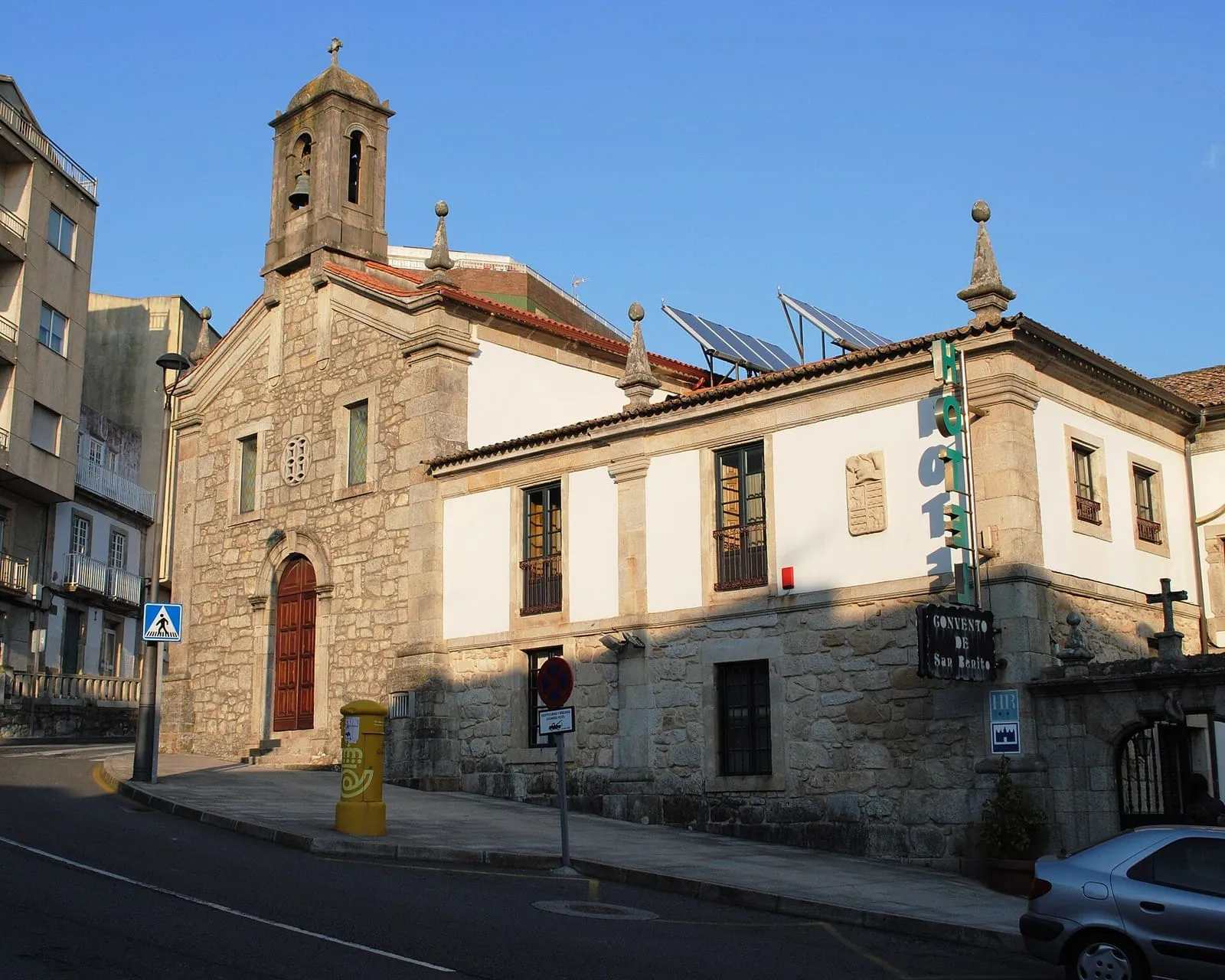 El convento de San Bieito de A Guarda, con su iglesia de piedra y campanario, junto a un edificio blanco en la calle