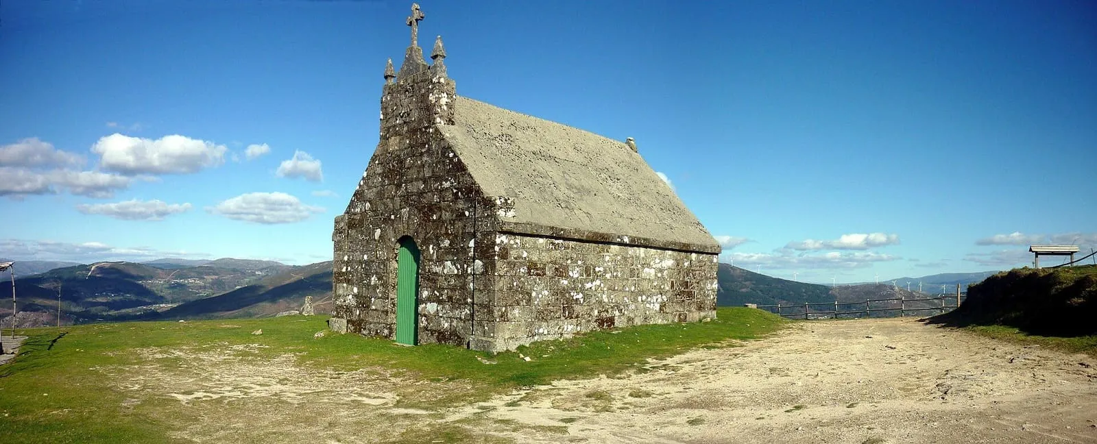 Ermita de piedra de San Nomedio en lo alto del monte, con montañas al fondo