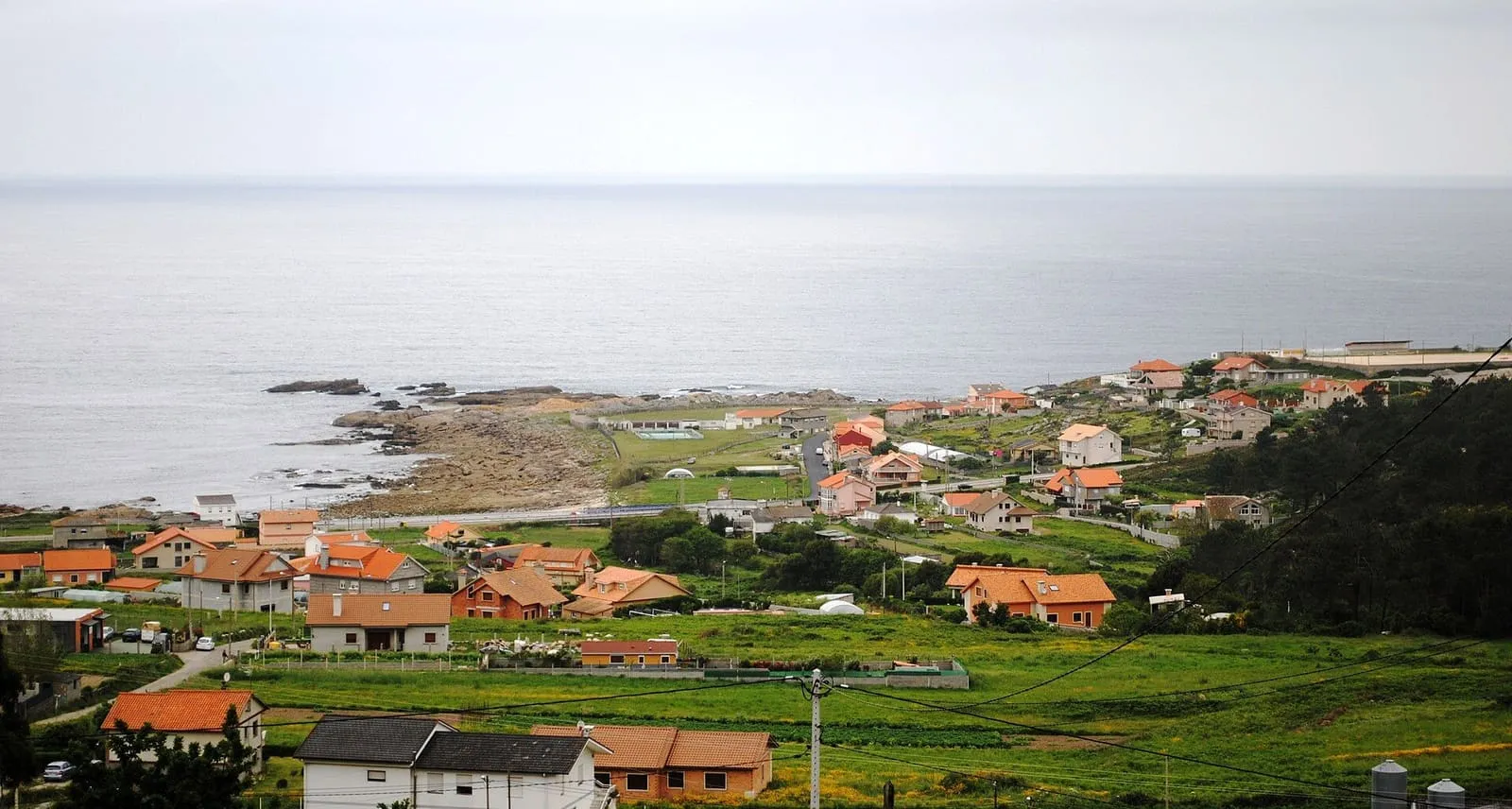 Casas de Mougás entre prados verdes frente a la costa atlántica