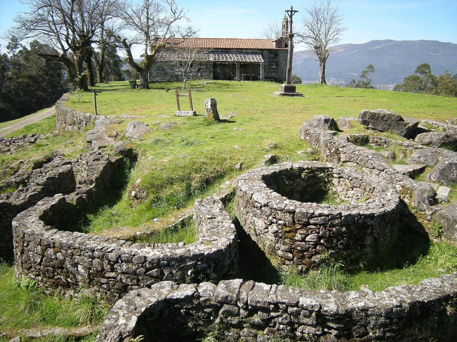 Viviendas circulares de piedra del castro de Troña, con una capilla al fondo
