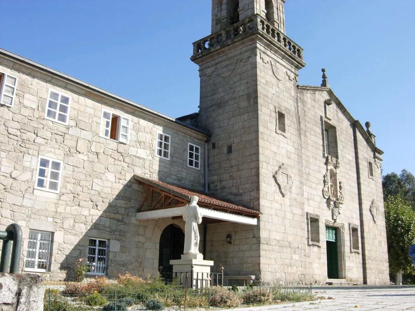 El convento de San Diego de Canedo, de piedra, con torre-campanario y el edificio conventual, con una escultura en la entrada