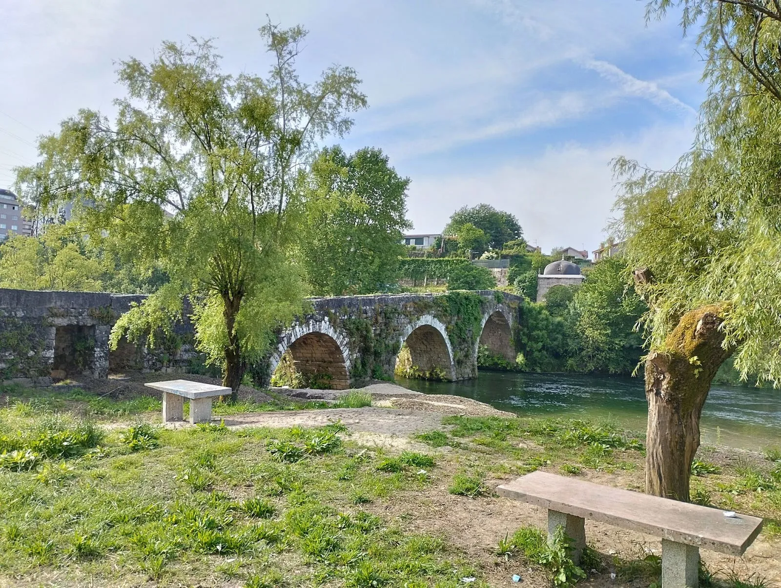 Arcos de piedra del puente de los Remedios, junto a un banco y árboles