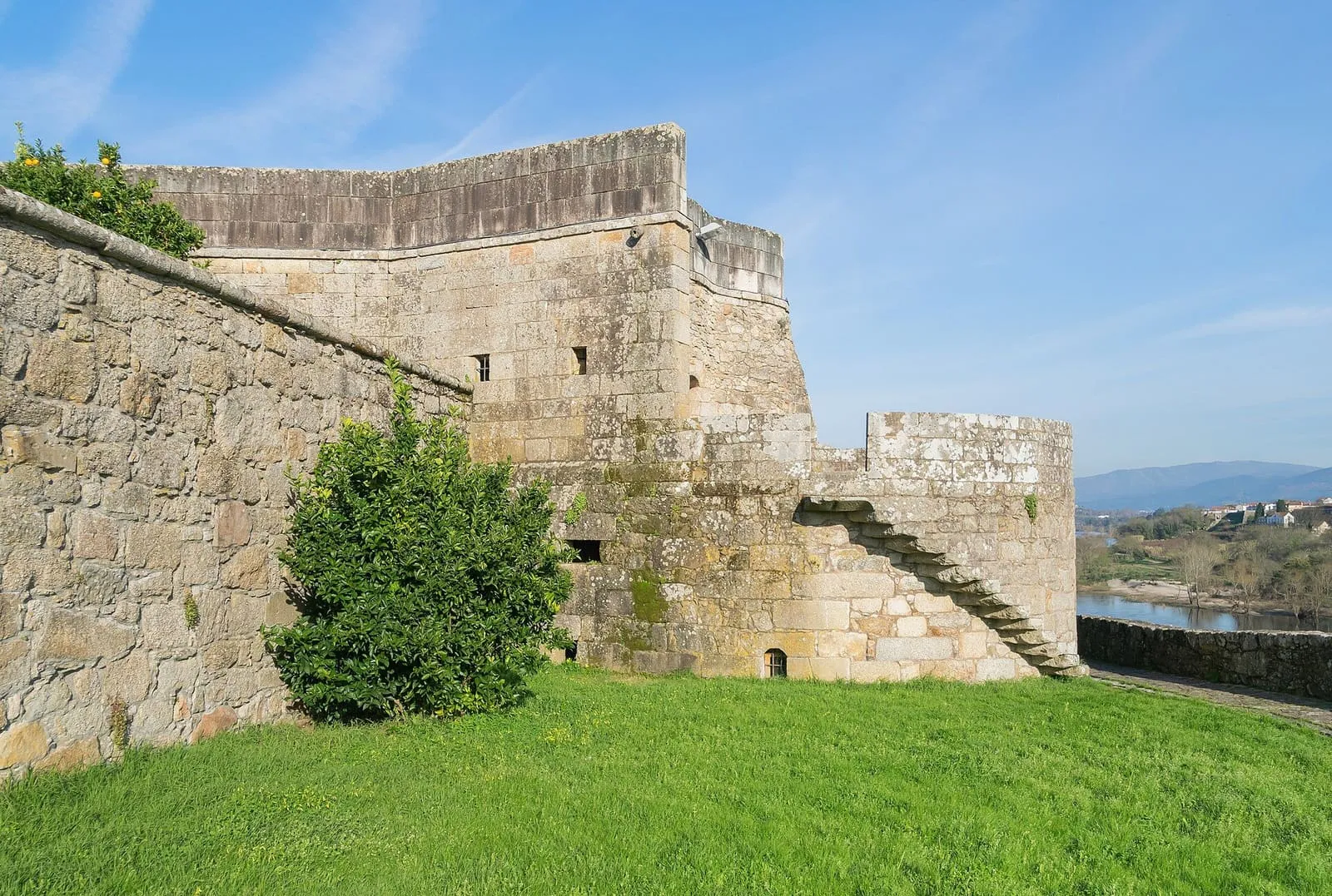 Muralla y baluarte de la fortaleza de Salvaterra de Miño sobre una explanada de hierba