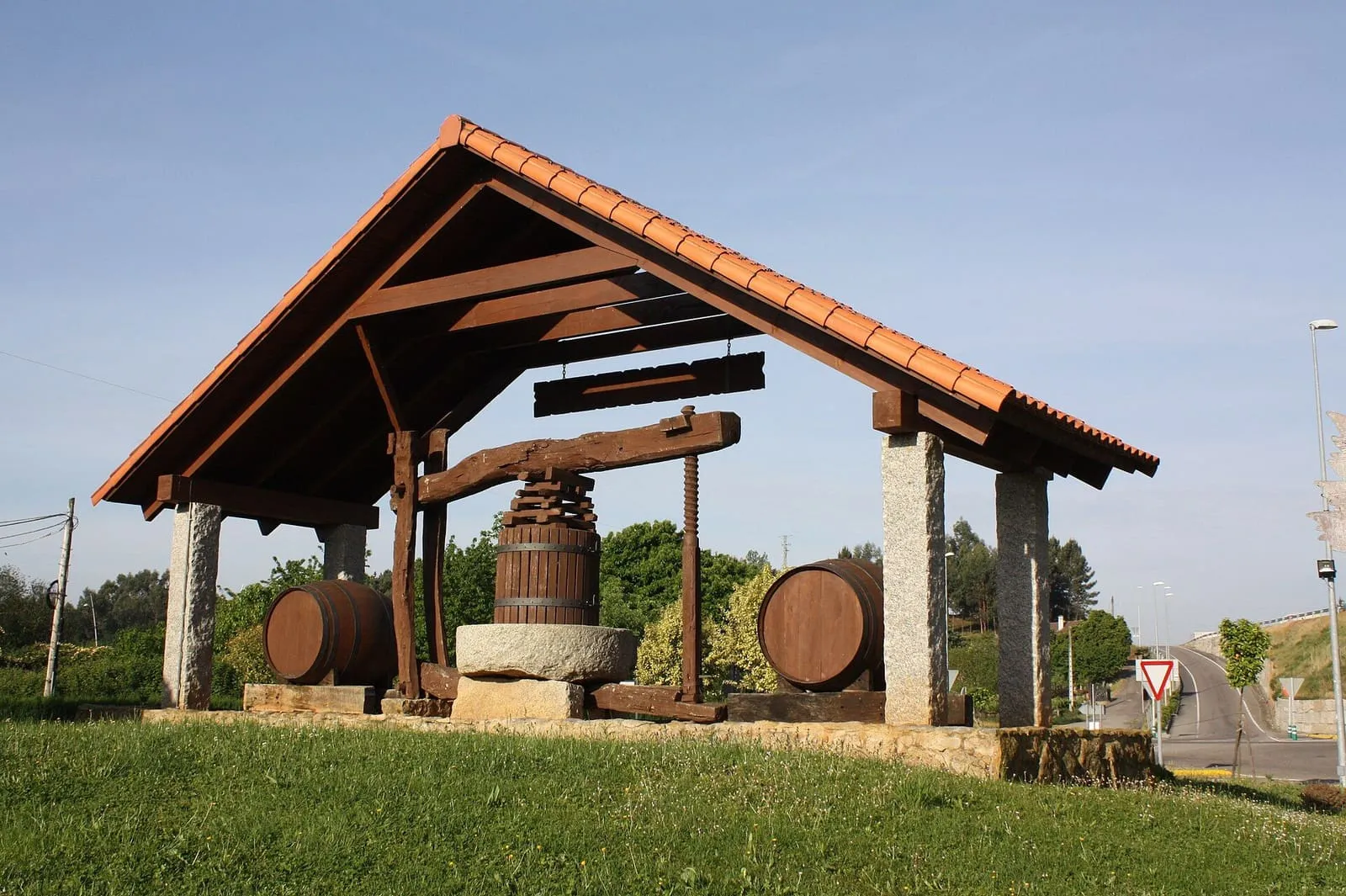 Prensa de vino de madera bajo un tejado, con barricas, en Salvaterra de Miño