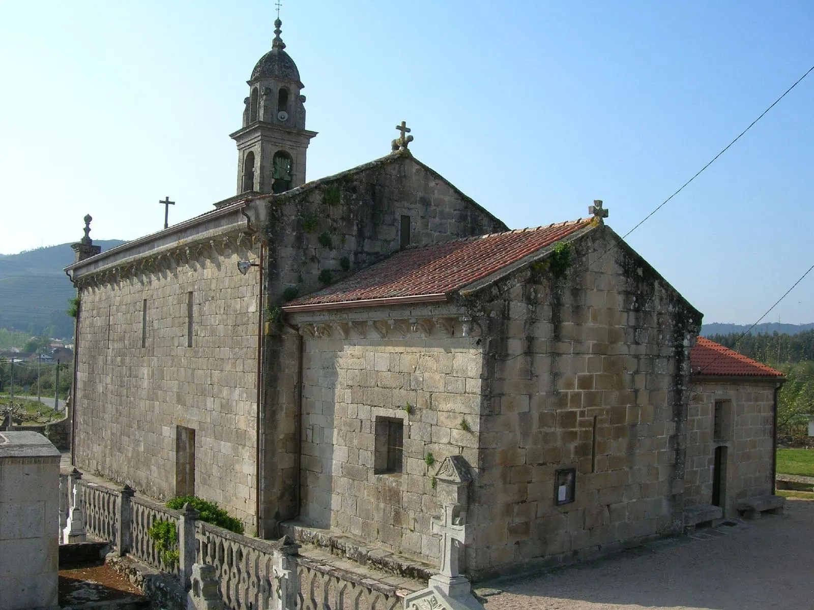 Iglesia de piedra de Santa María de Tomiño, con su campanario y el valle detrás