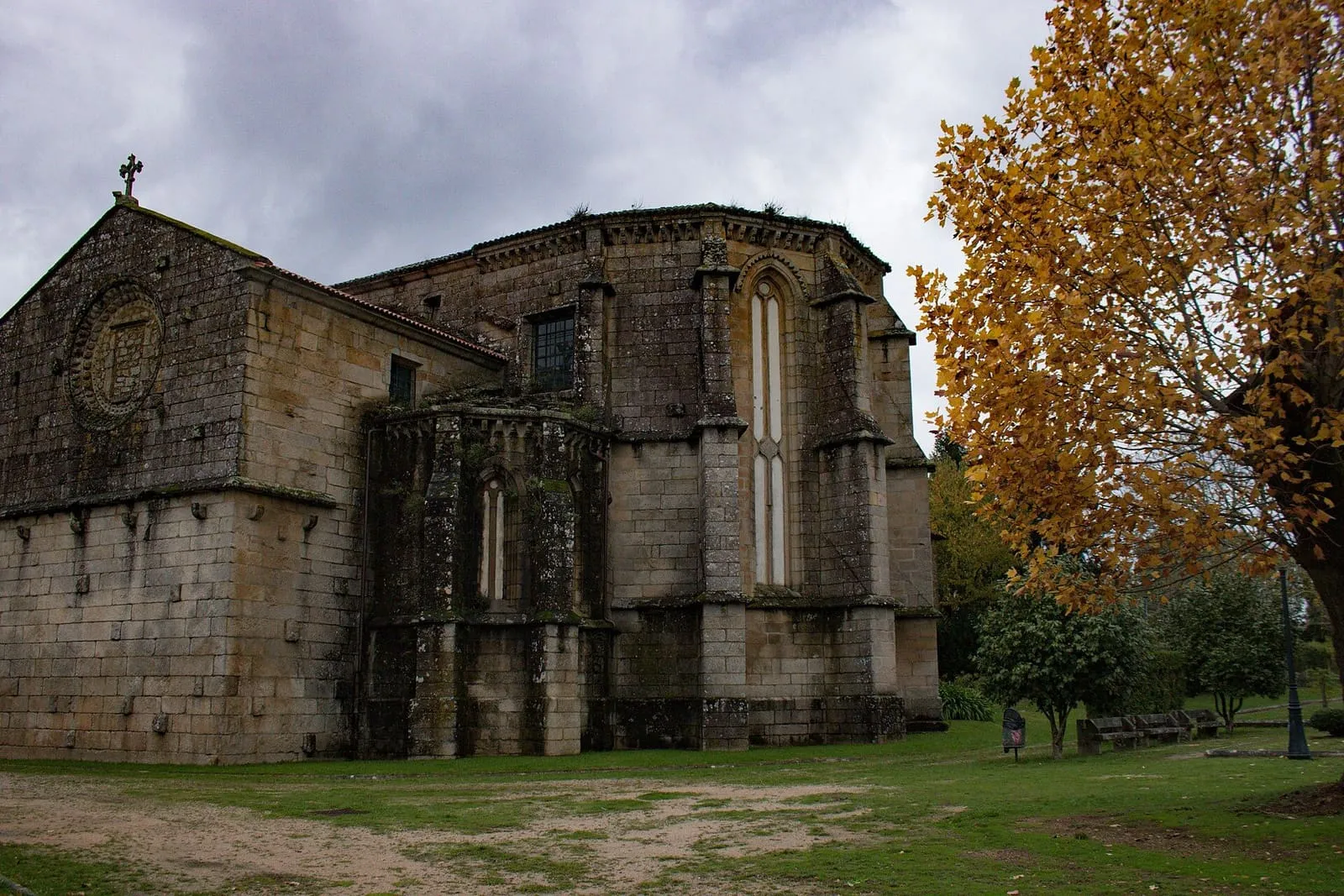 La iglesia de San Domingos, de piedra, con grandes ventanales góticos en el ábside, entre árboles de otoño