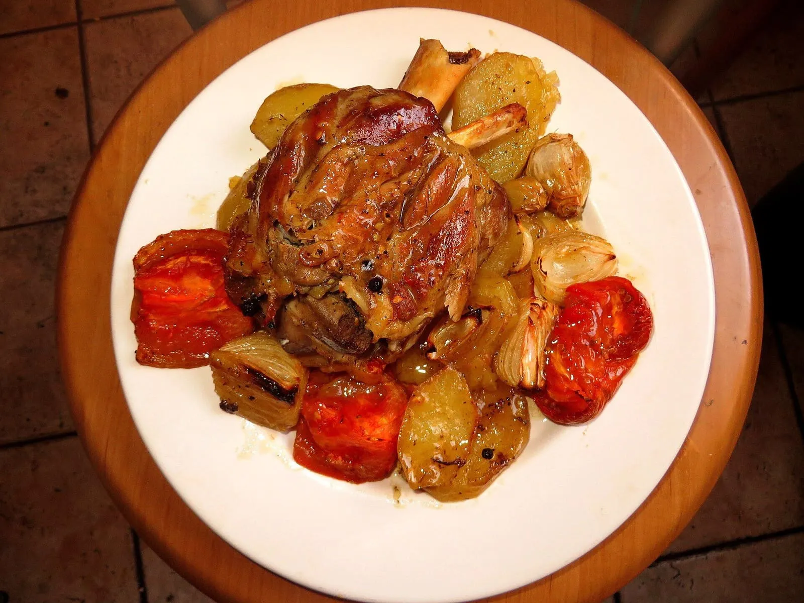 Codillo de cerdo asado con patatas y tomates en un plato