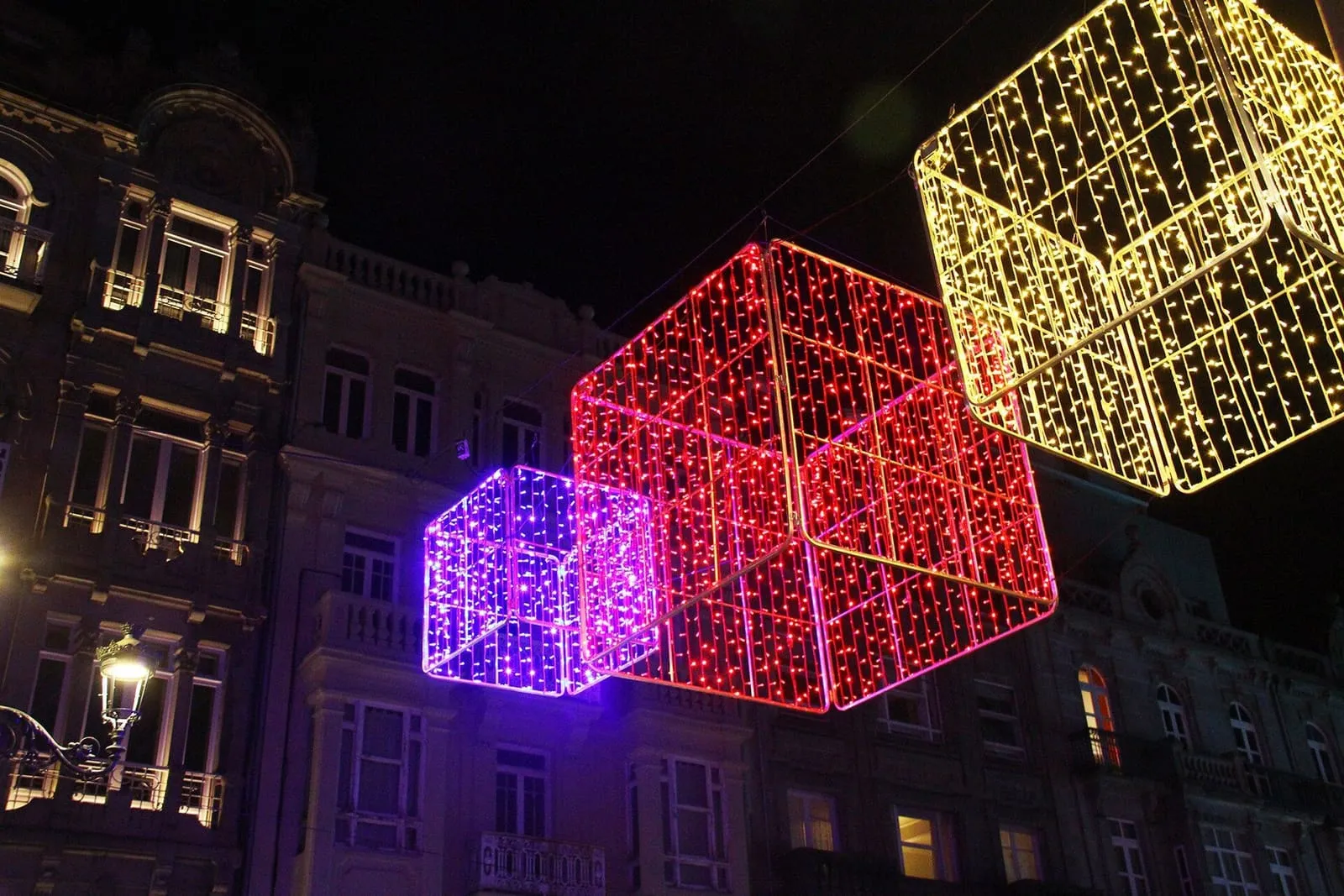 Cubos gigantes de luces de Navidad colgados sobre una calle de Vigo de noche