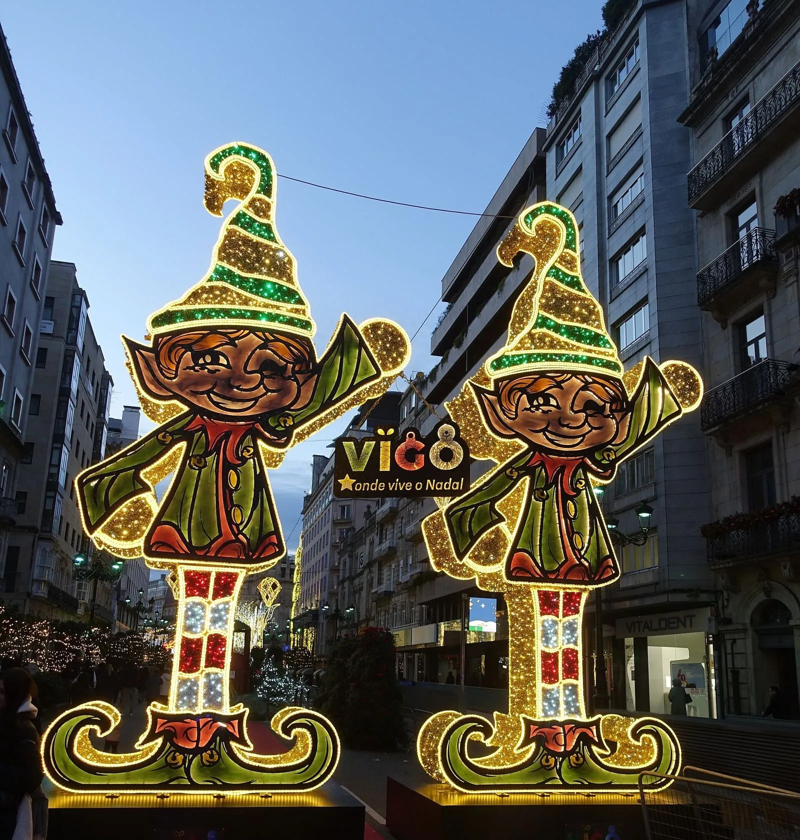 Dos elfos luminosos gigantes en una calle del centro de Vigo, con el cartel «Vigo, onde vive o Nadal»