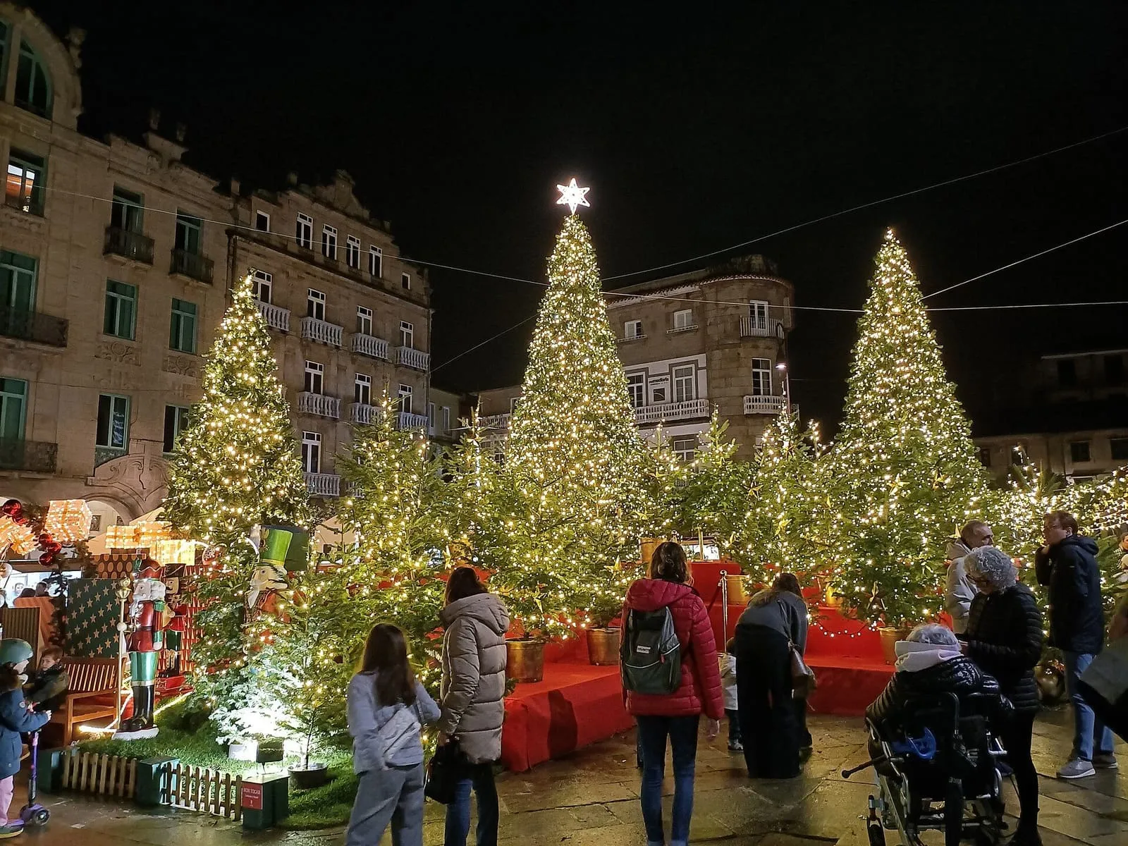 Árboles de Navidad iluminados y casetas del Poboado de Nadal en la Praza da Ferrería de Pontevedra, de noche