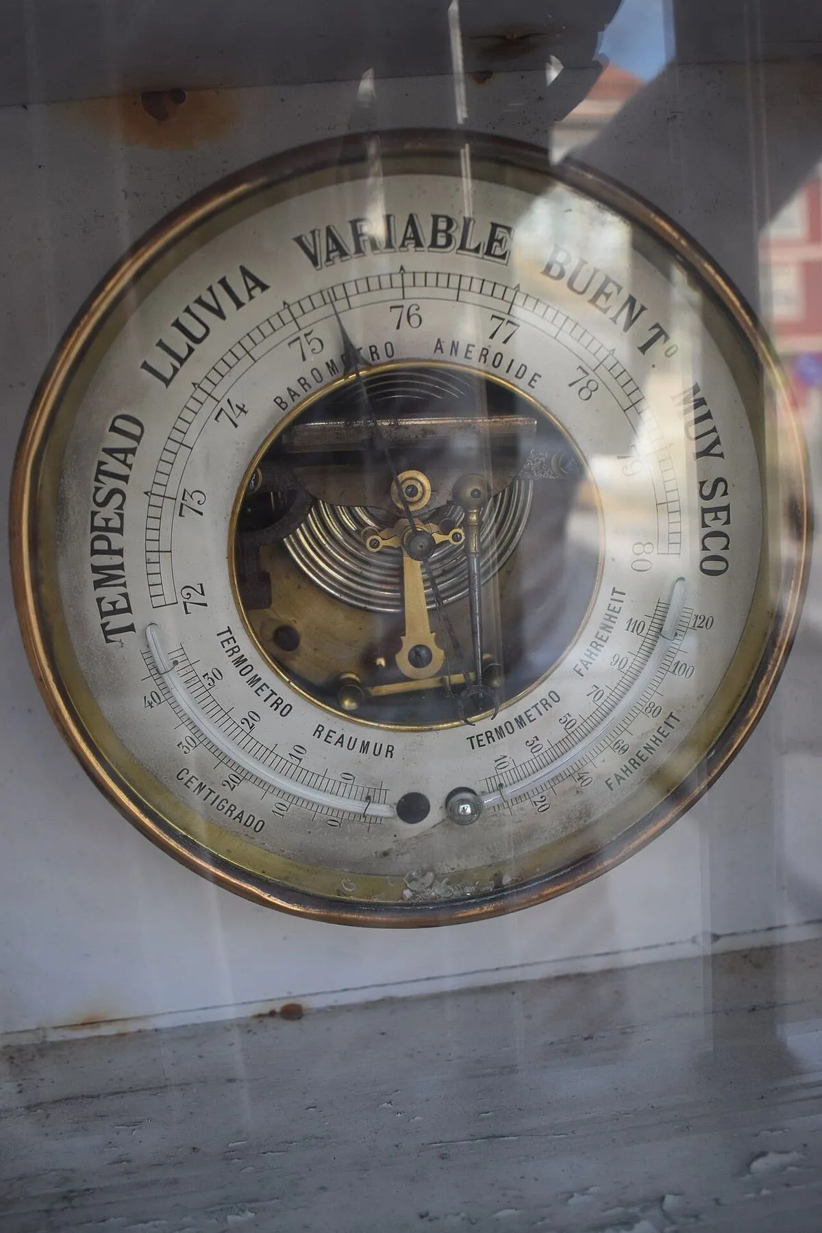 Un barómetro antiguo de latón y esfera blanca con las indicaciones de tempestad y tiempo seco