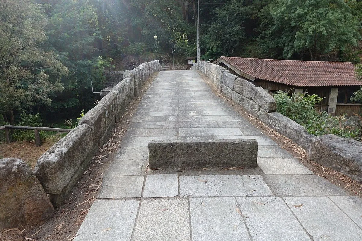 La calzada de losas de granito del puente, con muretes de piedra y una gran losa en el centro