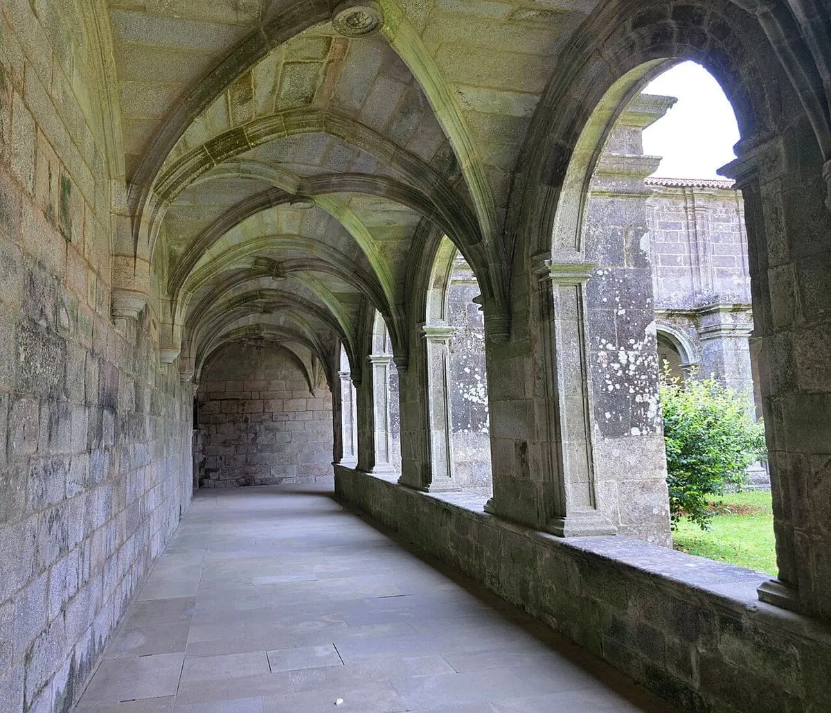 Galería del claustro de Armenteira con bóvedas de crucería y arcos de piedra abiertos al jardín
