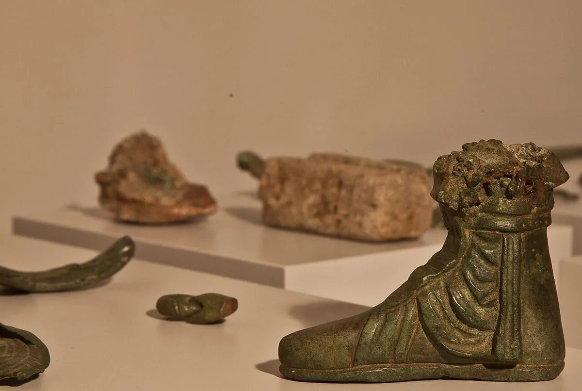 Un pie de bronce calzado con calceus senatorius, entre otros fragmentos metálicos en una vitrina