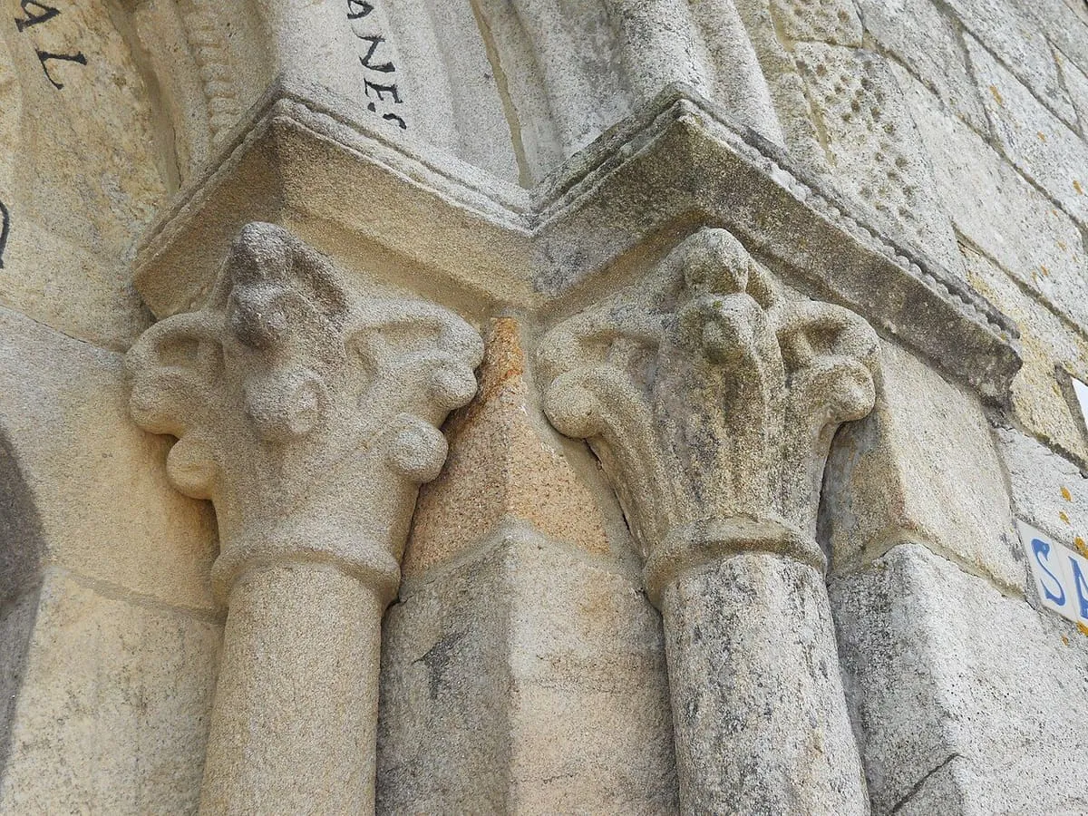 Capiteles románicos tallados con motivos vegetales en una portada de granito