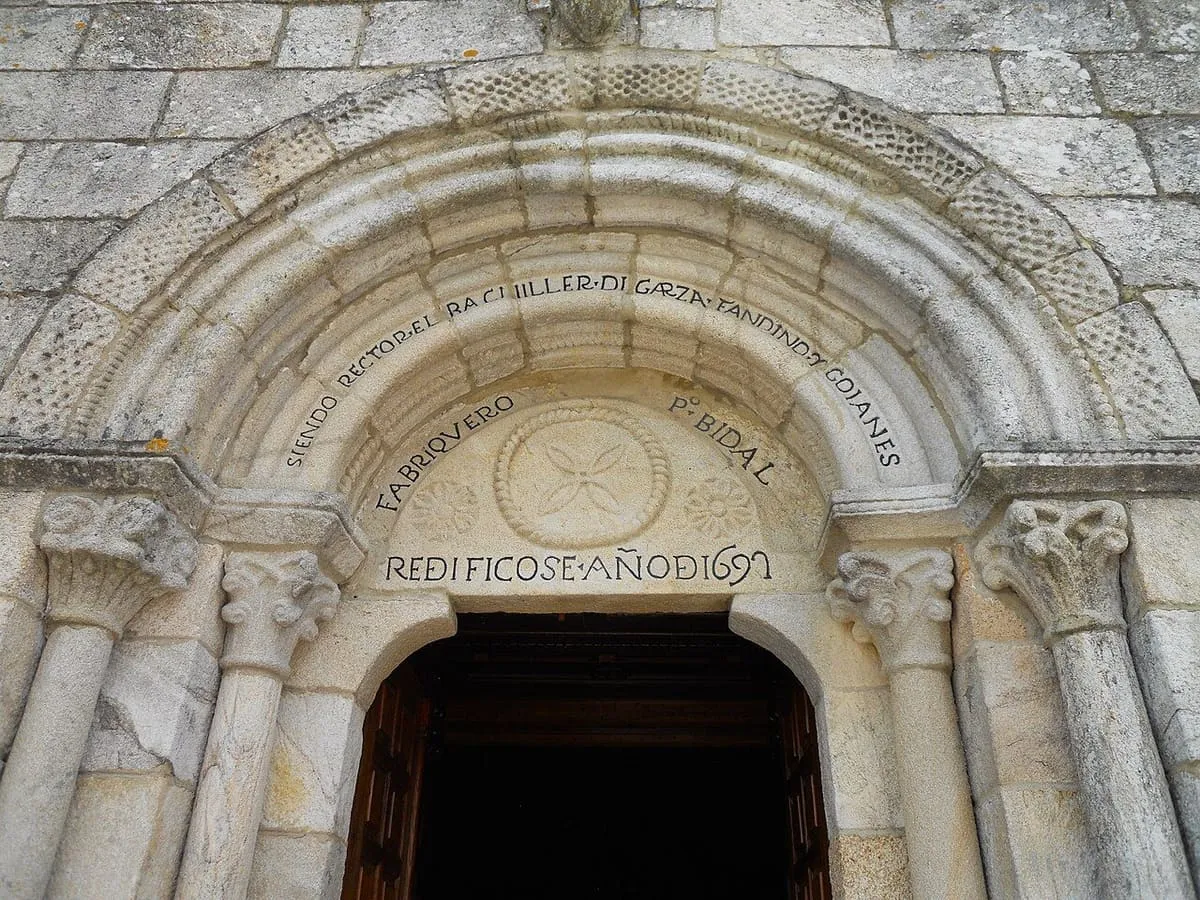 Portada románica de arcos de medio punto con una inscripción y un crismón sobre la puerta