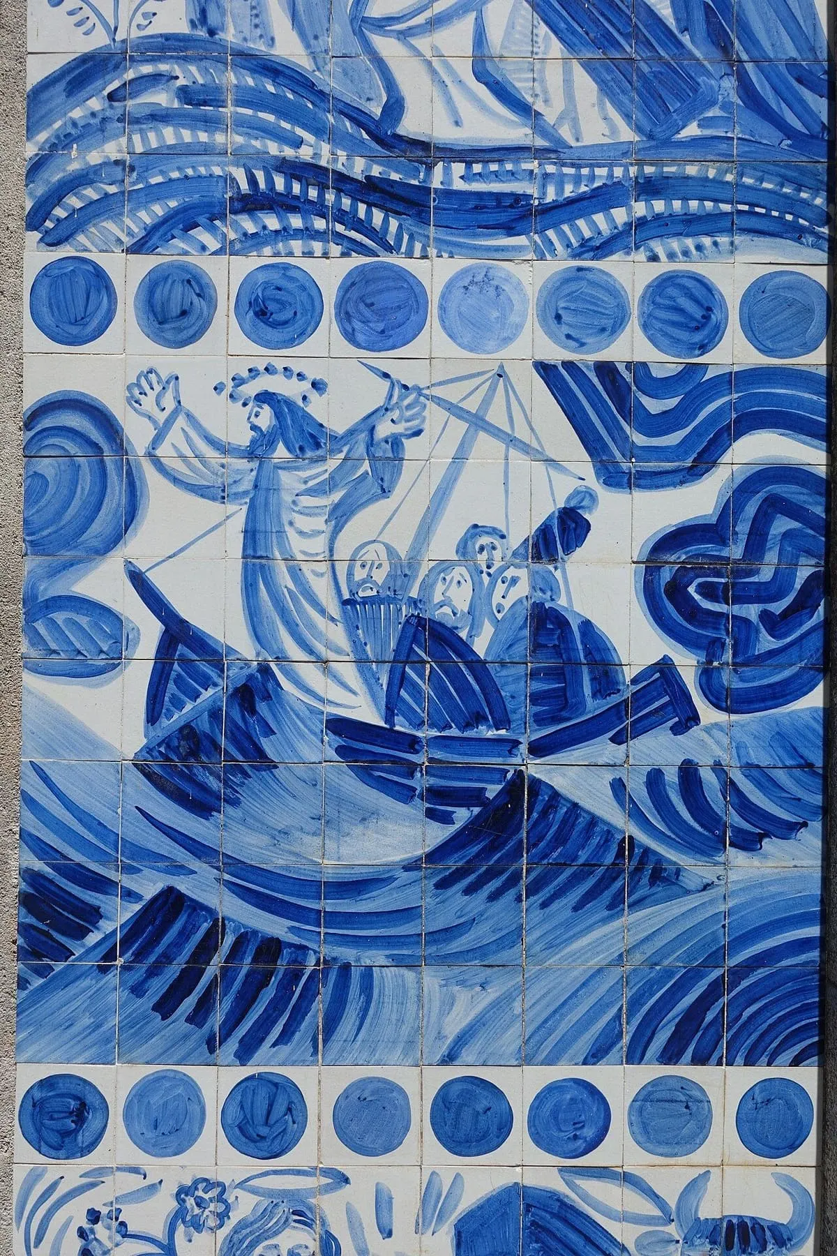 Mural de azulejos azules con pescadores en una barca en el mar, en la fachada de la iglesia de Ons