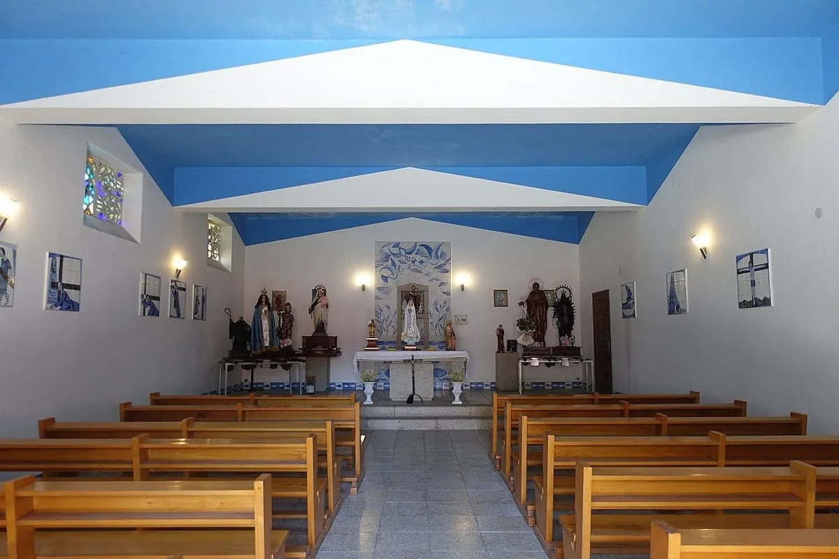 Interior sencillo de la iglesia de San Xoaquín, con bancos de madera y paredes blancas y azules