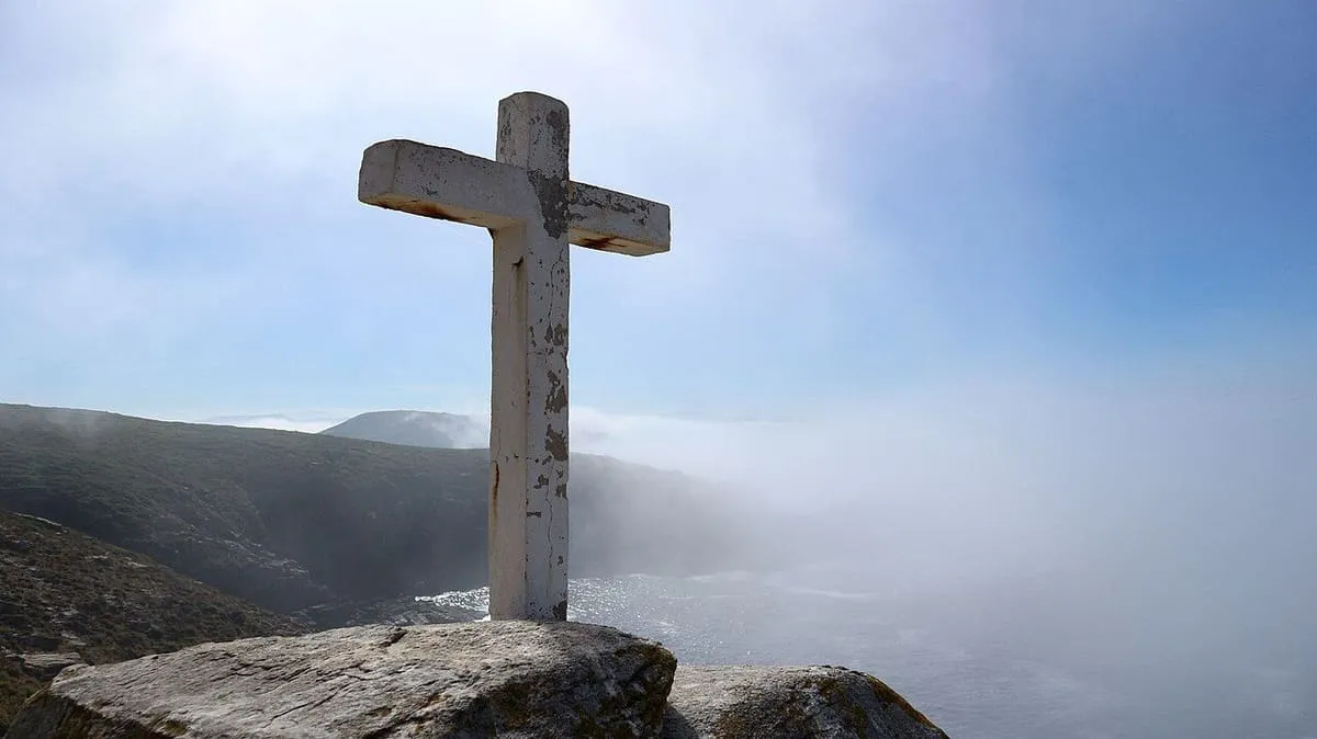 Una cruz de piedra sobre un peñasco junto al mar y la bruma en la costa de Ons