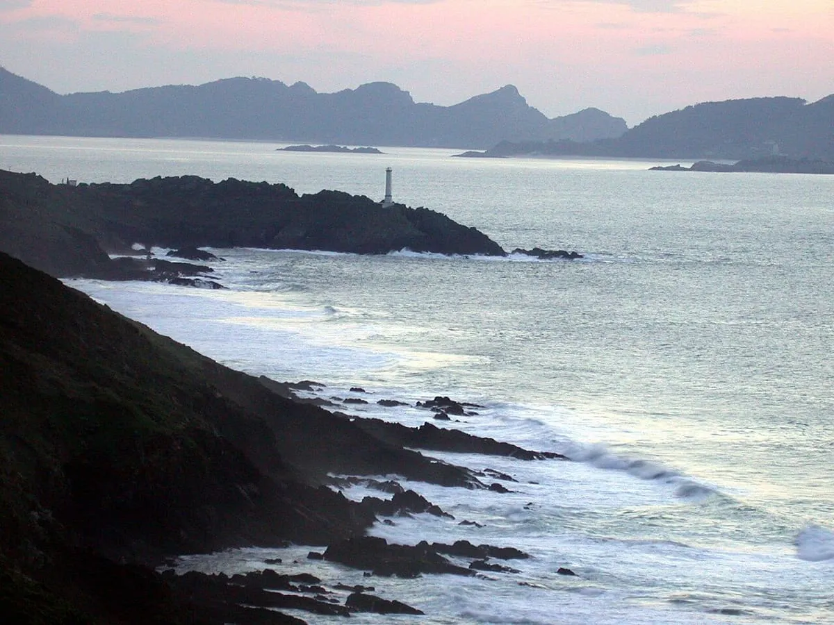 Costa rocosa y oleaje en Cabo Home, con el faro al fondo