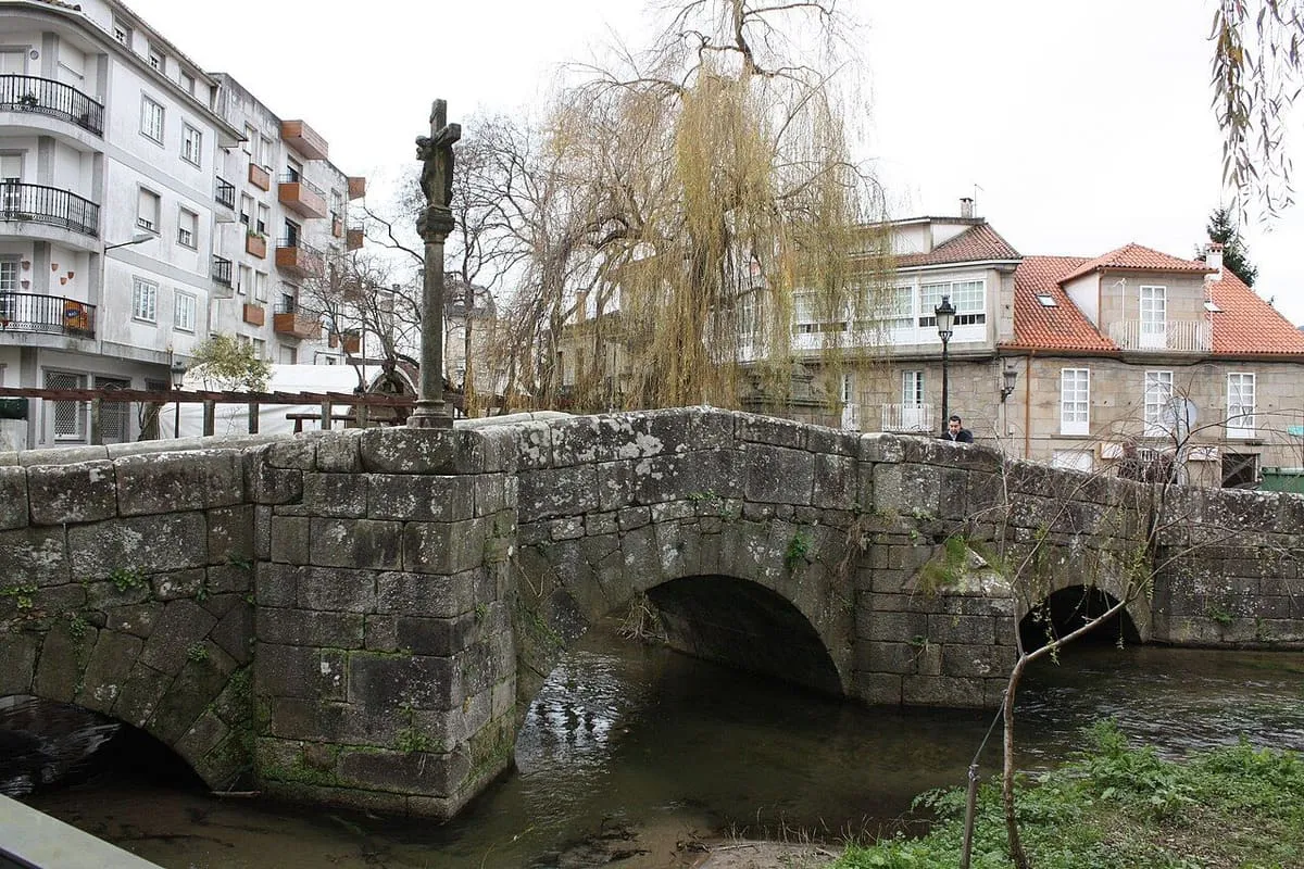 Los arcos de la ponte da Bermaña vistos desde la orilla, con un cruceiro en un apartadero